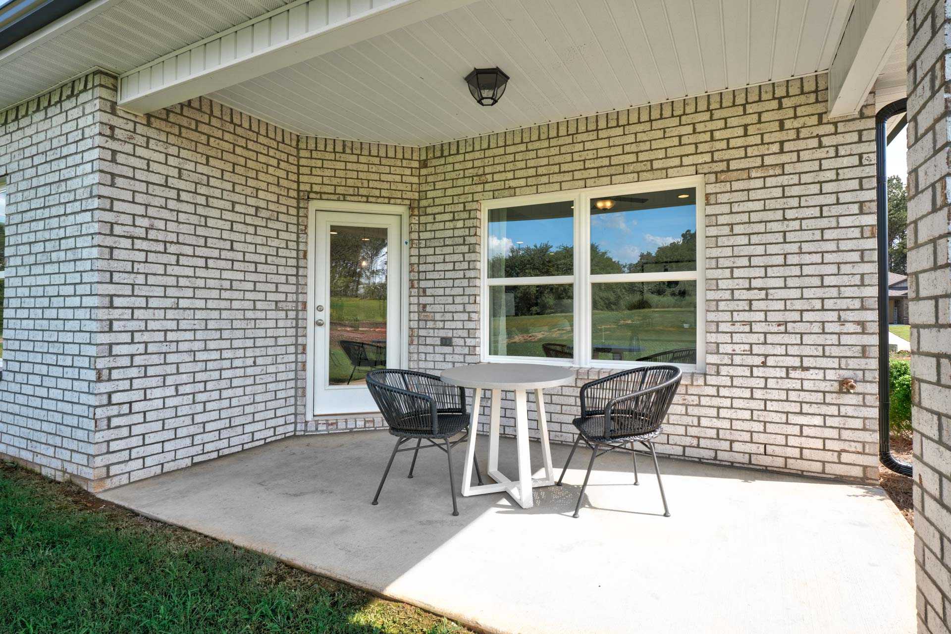 Covered patio with white brick walls, wicker chairs, round table at Blue Spring in Huntsville Alabama