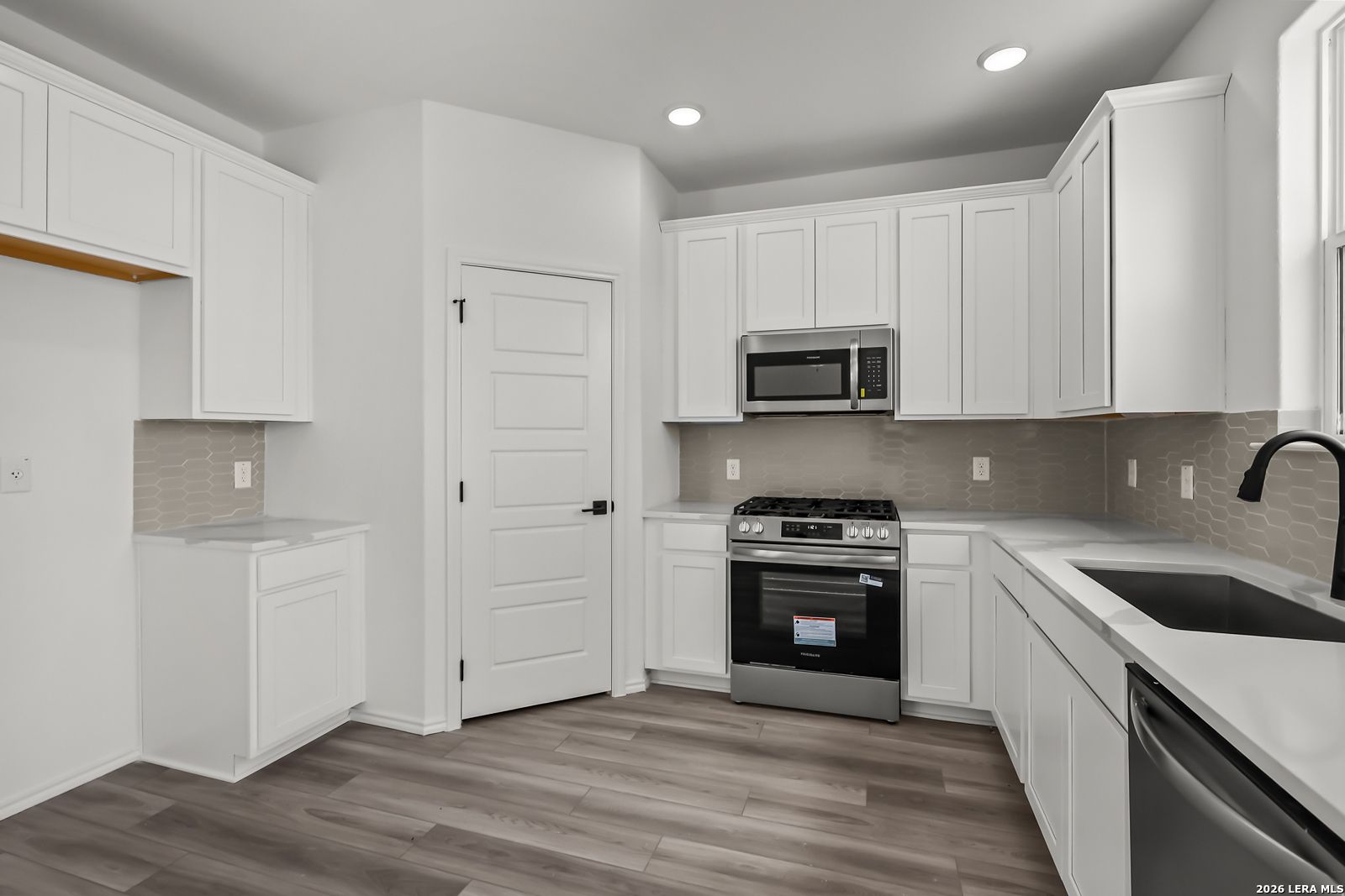 Modern kitchen with white cabinets and stainless appliances in The Florence B floor plan at Meadows at Oak Creek, San Antonio.