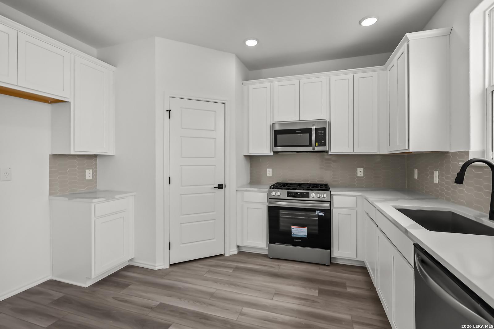 Modern kitchen with white cabinets and stainless appliances in The Florence B floor plan at Meadows at Oak Creek, San Antonio.