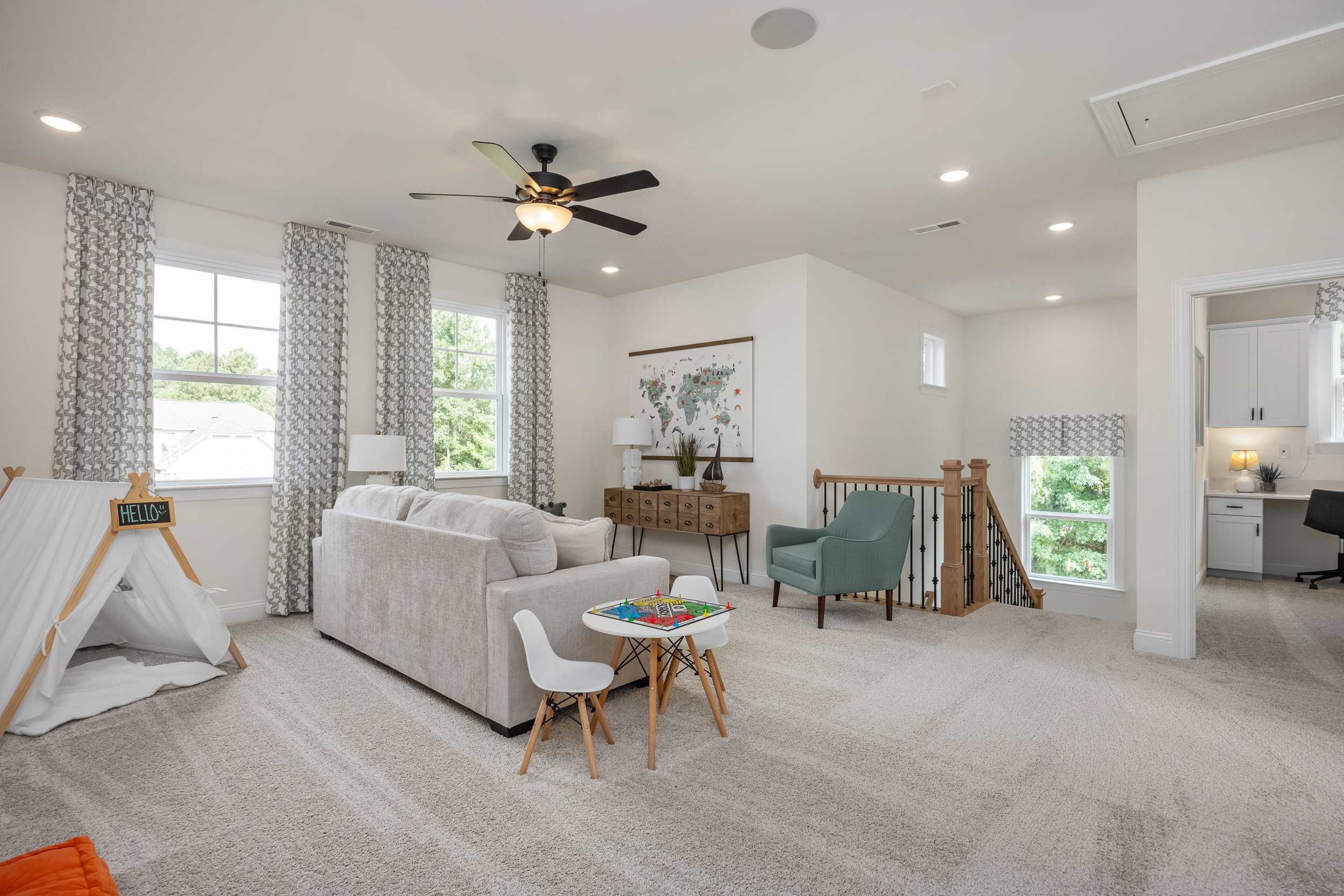 Cozy family room at Laneridge Estates in Raleigh NC with gray sofa, kids teepee tent, play table and open staircase