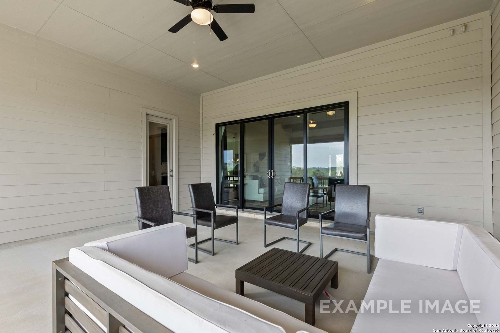 Covered patio with wicker seating, coffee table, ceiling fan, and sliding doors in Davidson Homes The Summerlin B, Castroville, Texas