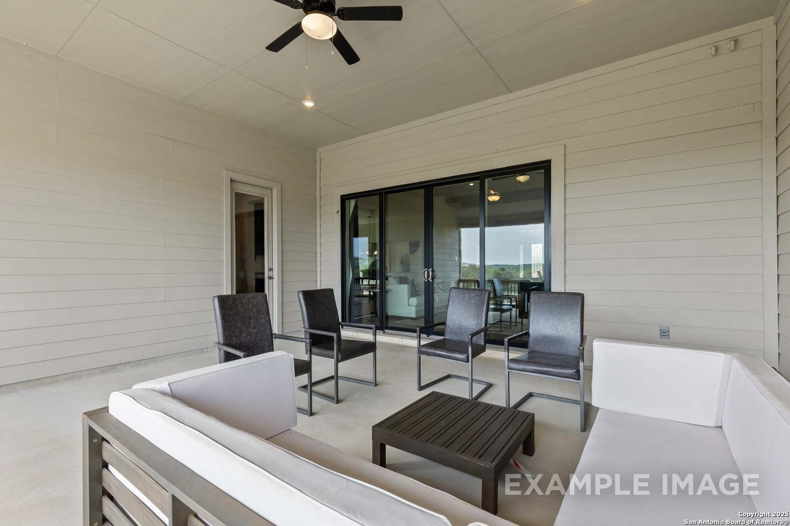 Covered patio with wicker seating, coffee table, ceiling fan, and sliding doors in Davidson Homes The Summerlin B, Castroville, Texas