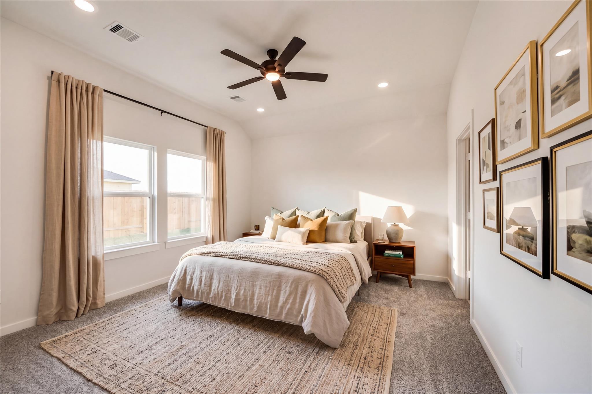 Bright, cozy bedroom with neutral decor and ceiling fan in The Riviera C floor plan at River Ranch Meadows, Dayton, Texas.