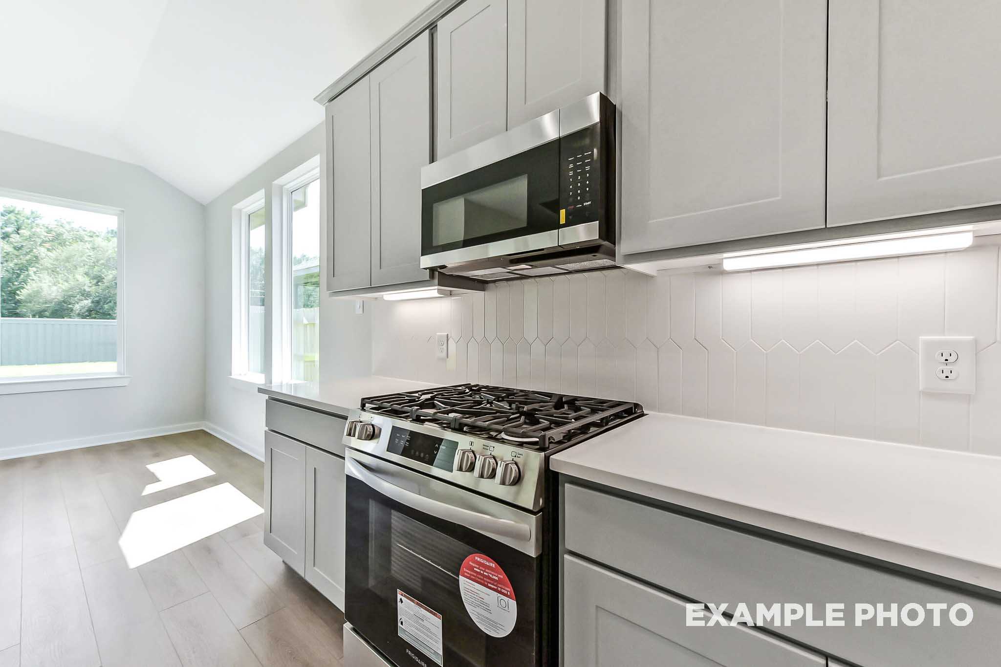 Modern kitchen in The Sequoia Davidson Homes plan featuring white shaker cabinets, stainless steel oven, and subway tile backsplash