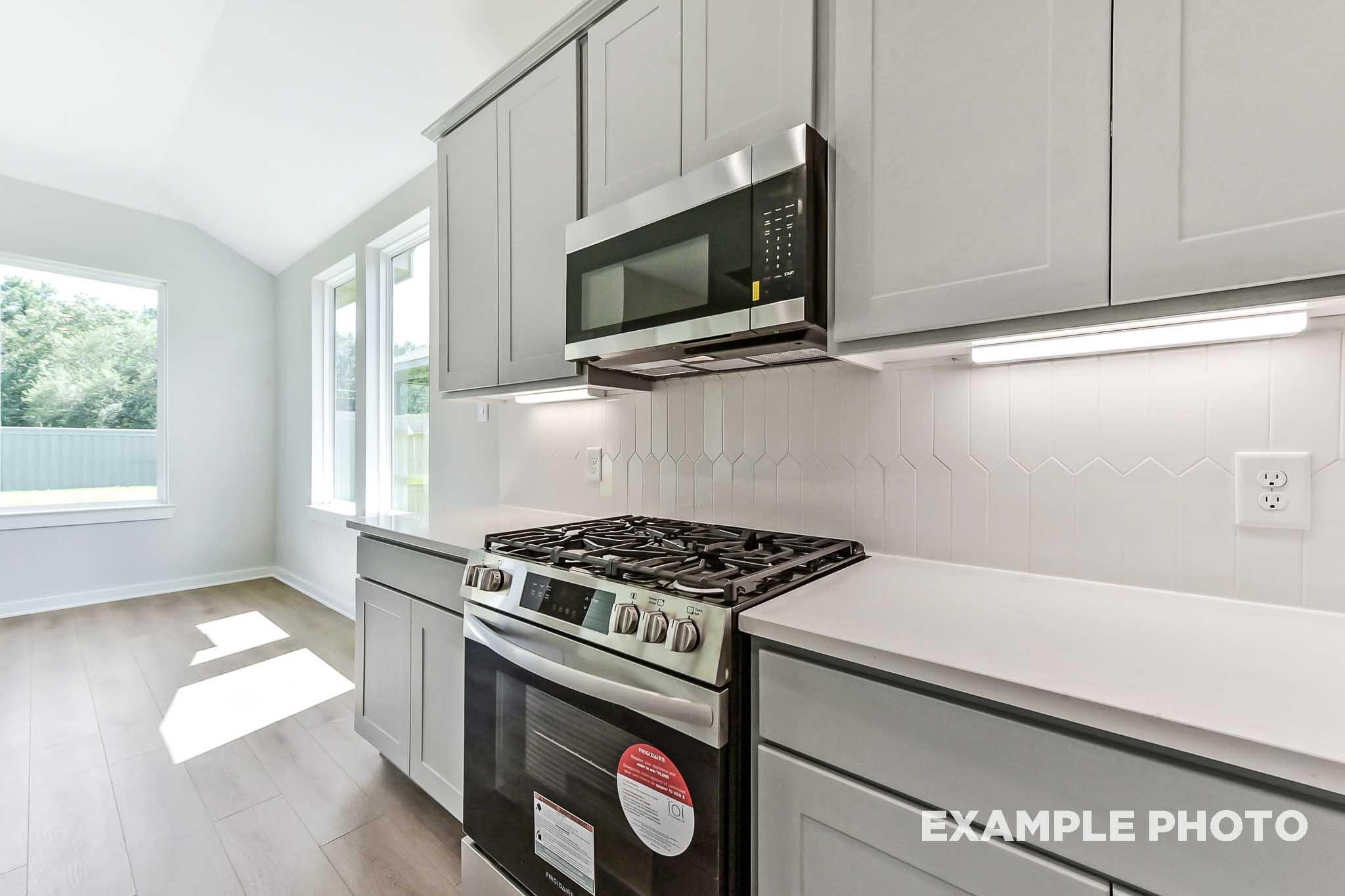 Modern kitchen in The Sequoia Davidson Homes plan featuring white shaker cabinets, stainless steel oven, and subway tile backsplash