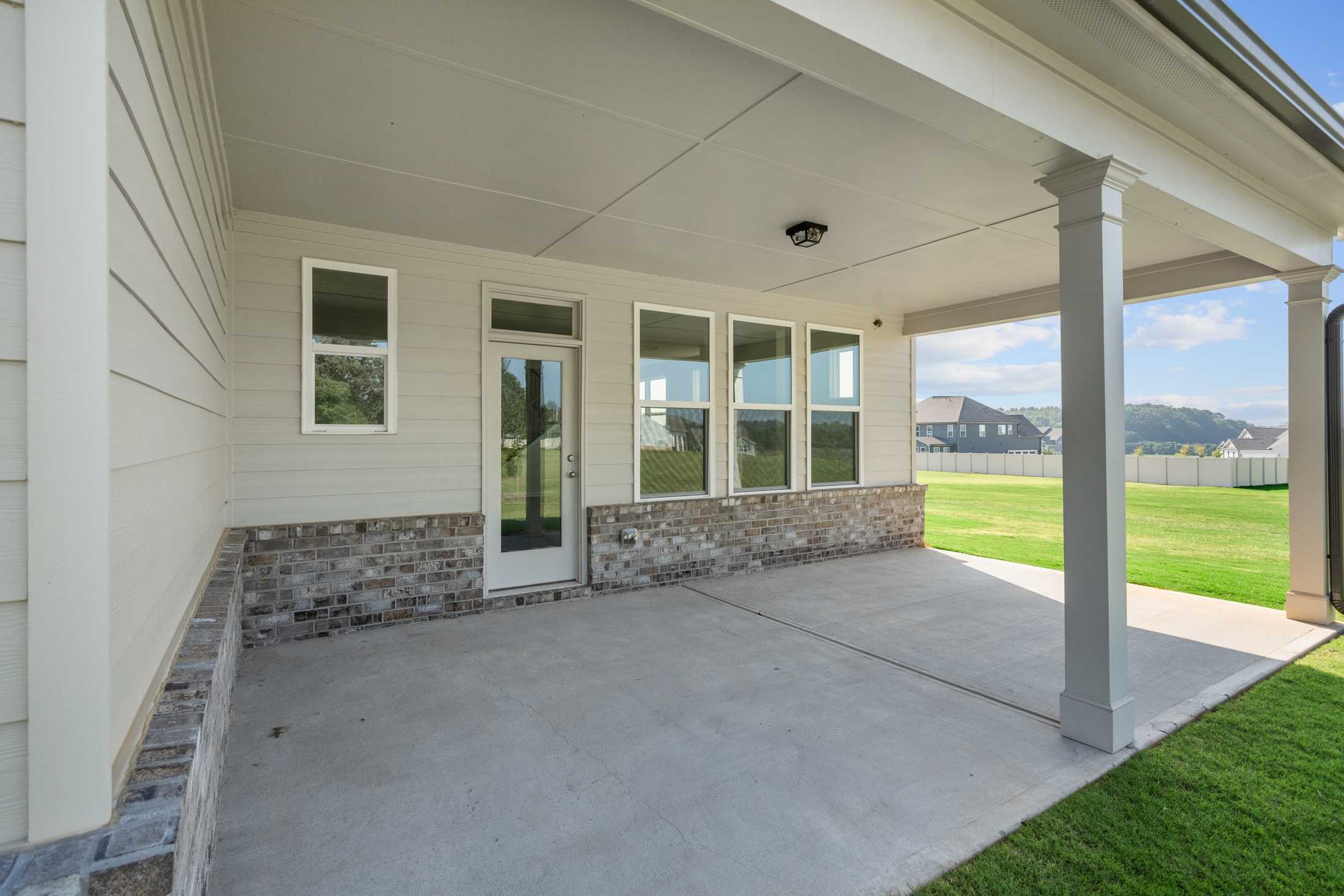 Spacious covered patio with brick base, large windows, and ceiling fan at Everleigh in Locust Grove, Georgia by Davidson Homes