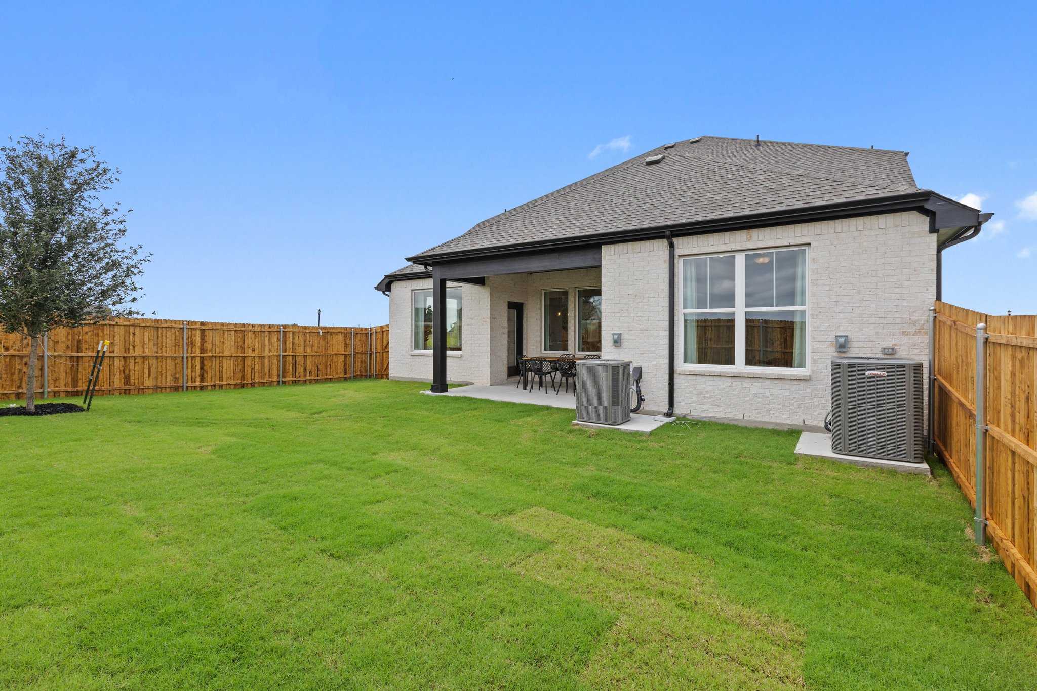 Two-story brick Sequoia N home with covered patio, large windows, and fenced grassy backyard in Waverly Estates, Josephine, Texas