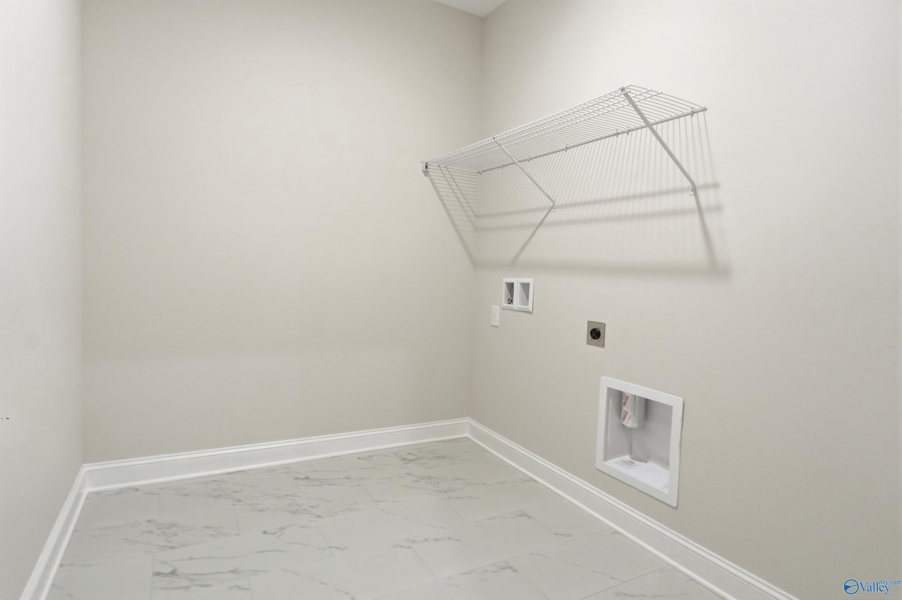 Spacious laundry room featuring utility sink, wire shelving, and marble flooring in Davidson Homes The Finleigh, Briercreek, Meridianville, Alabama