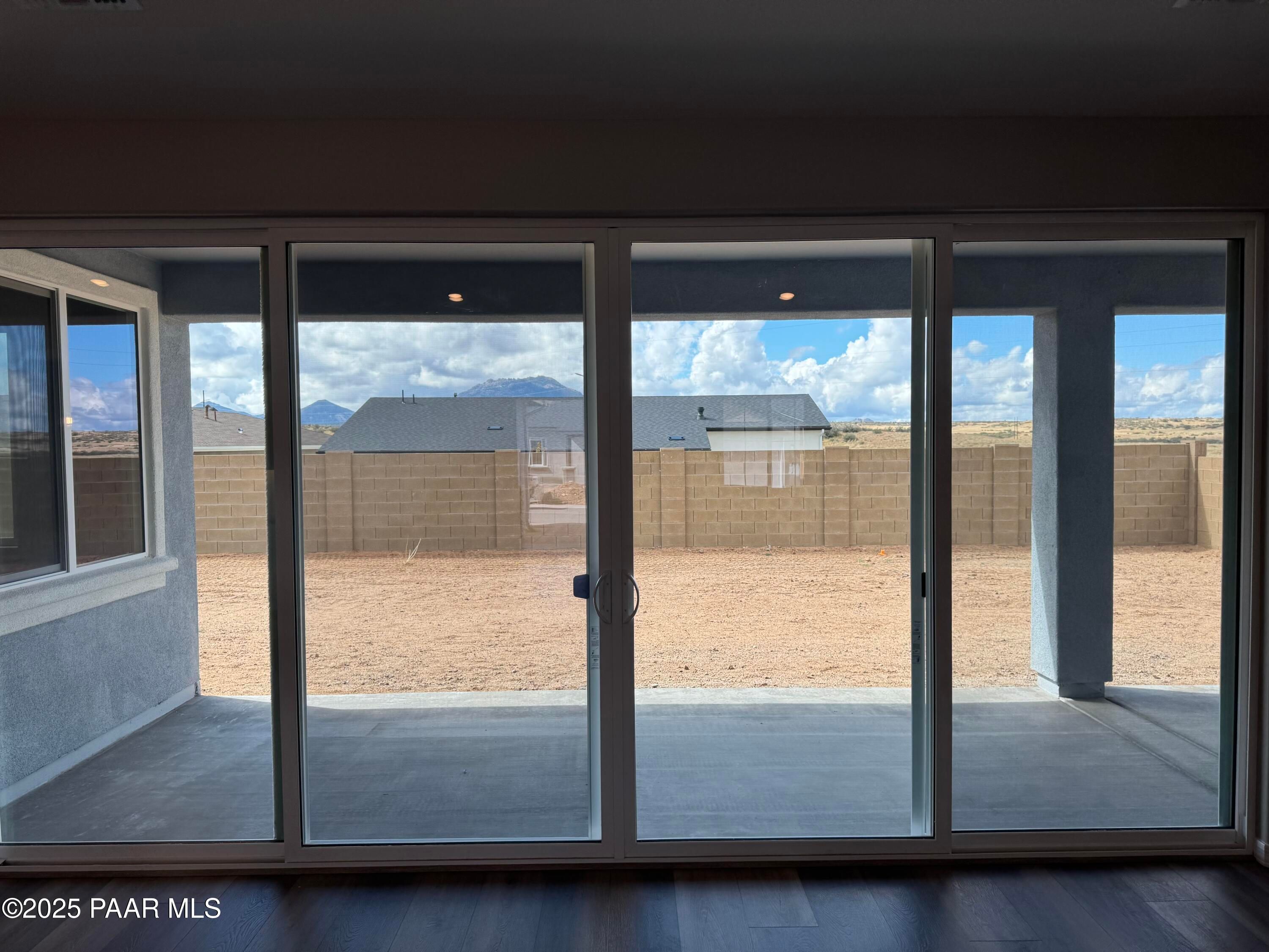 Expansive sliding glass doors revealing covered patio and desert backyard with mountain views in Davidson Homes The Monarch A, Prescott, Arizona