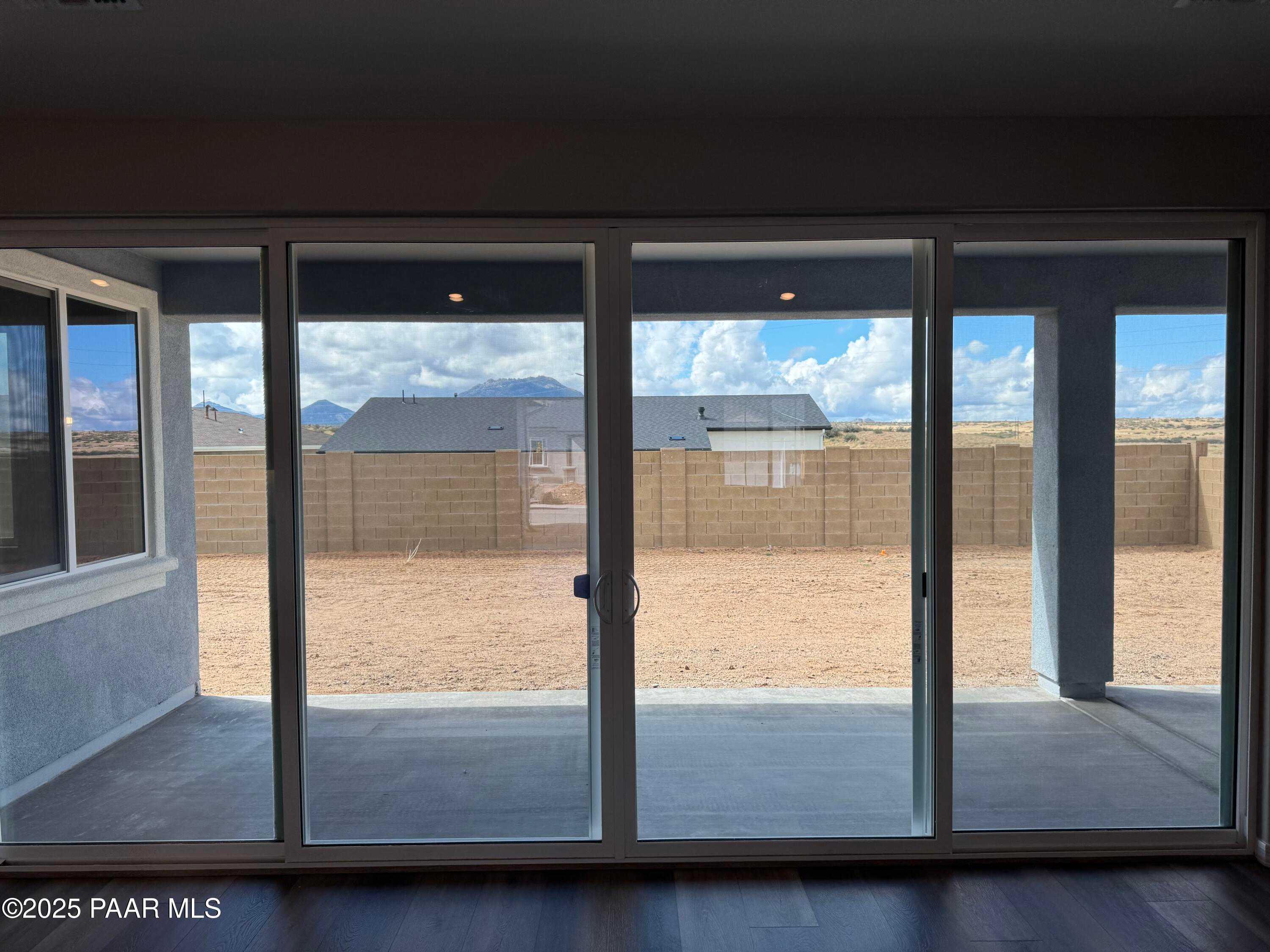 Expansive sliding glass doors revealing covered patio and desert backyard with mountain views in Davidson Homes The Monarch A, Prescott, Arizona
