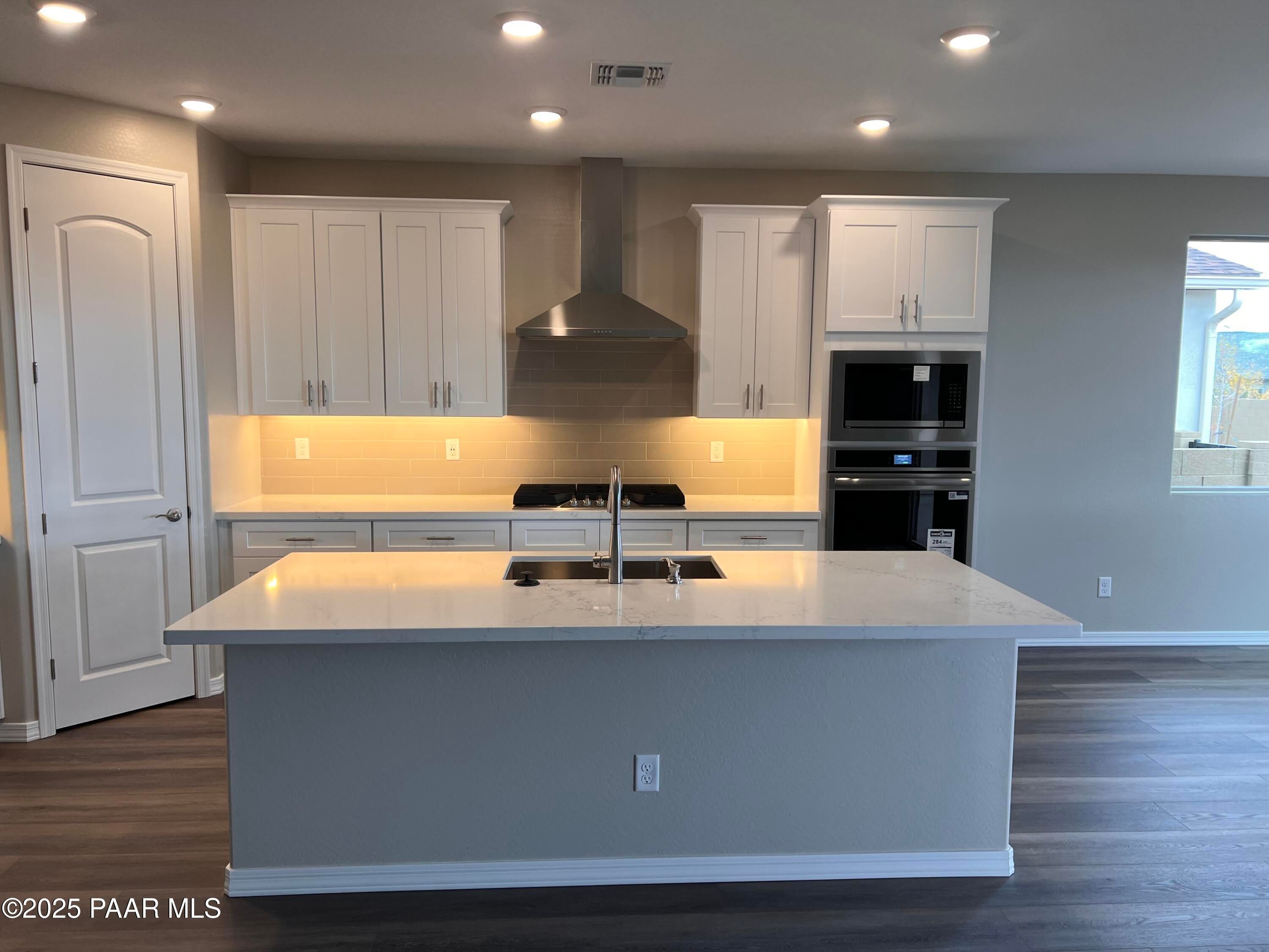 Modern kitchen featuring white shaker cabinets, quartz island sink, stainless steel range and double oven in Davidson Homes The Harmony A, Prescott Valley, Arizona