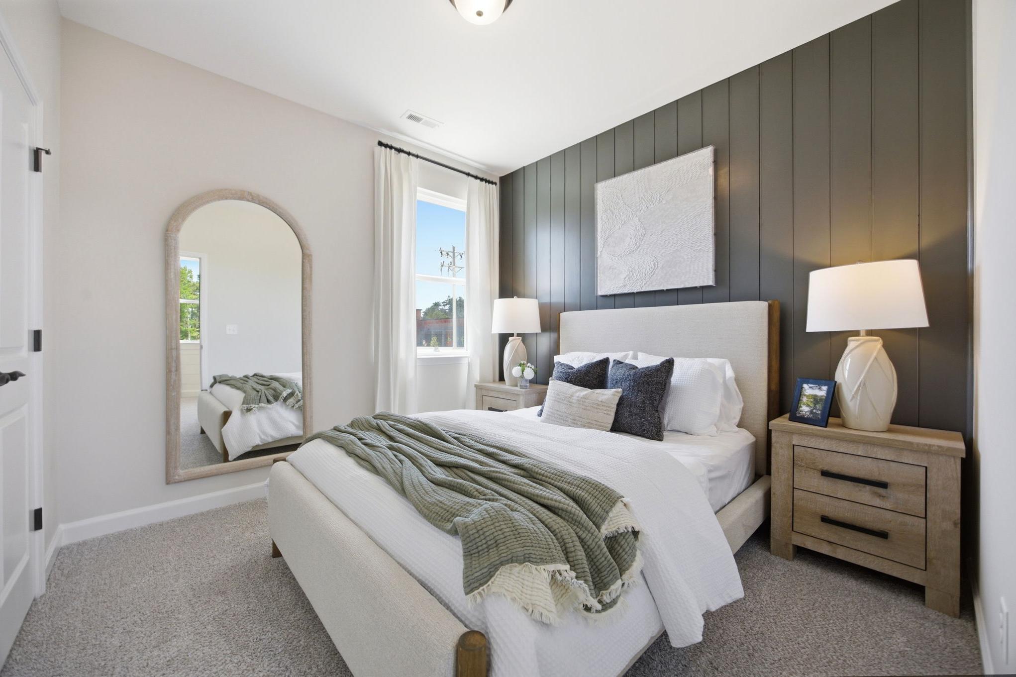 Spacious bedroom at Forestville Yard in Knightdale NC with king bed, gray shiplap accent wall, arched mirror, and bedside lamps