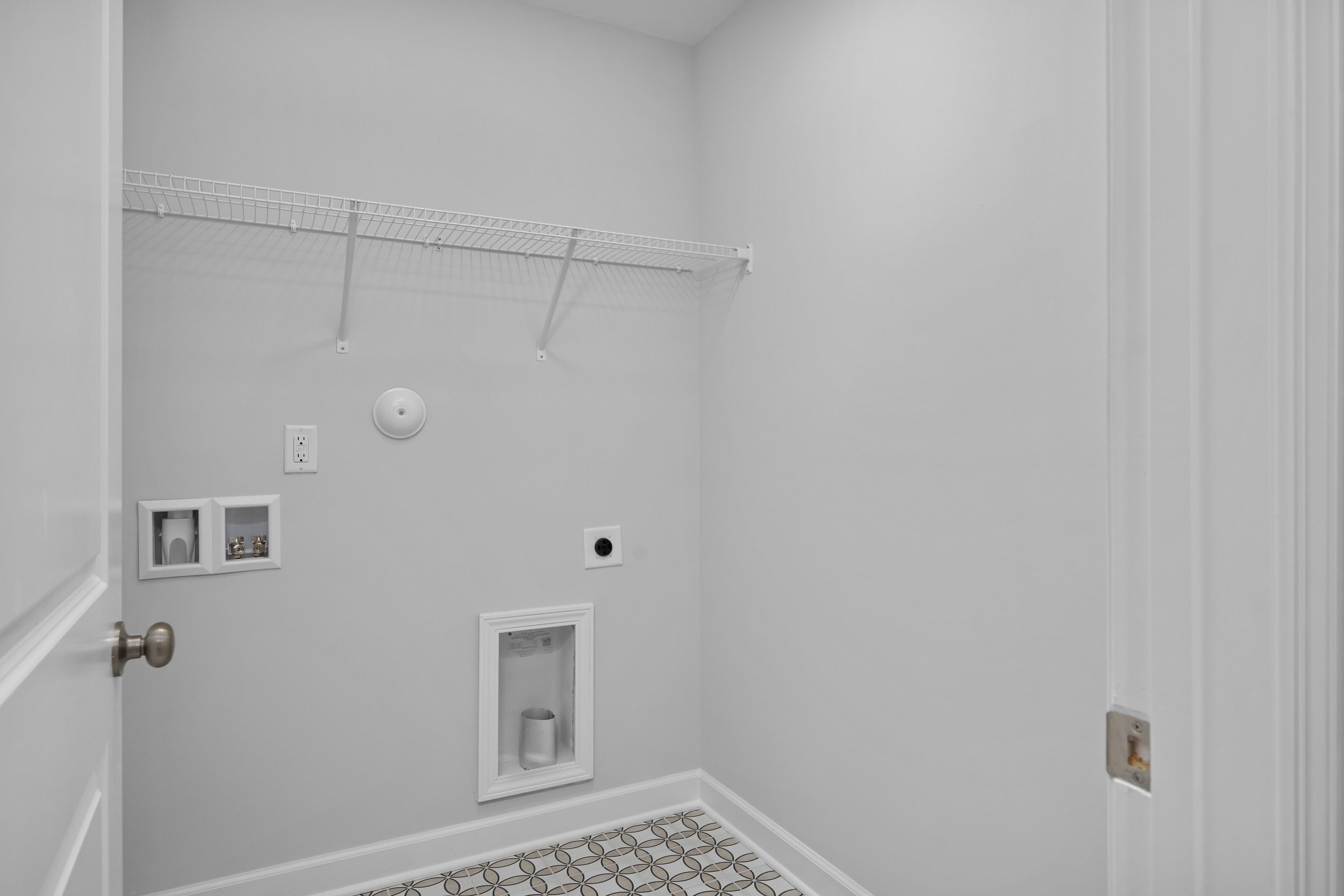 Laundry room in The Durham featuring wire shelving, utility hookups, and patterned tile flooring.