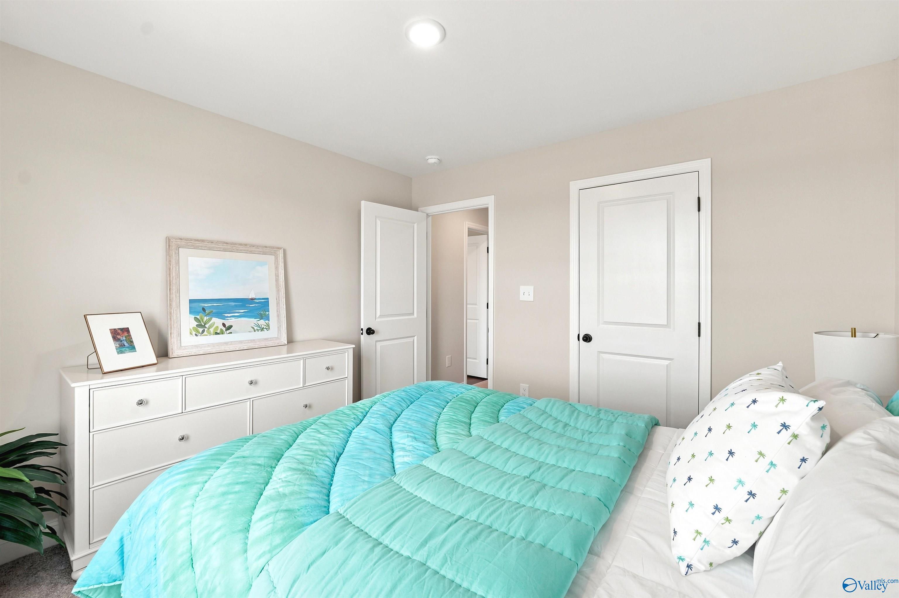 Bright secondary bedroom with coastal decor and teal bedding in The Burton B floor plan at Heritage Lakes, New Market, AL.