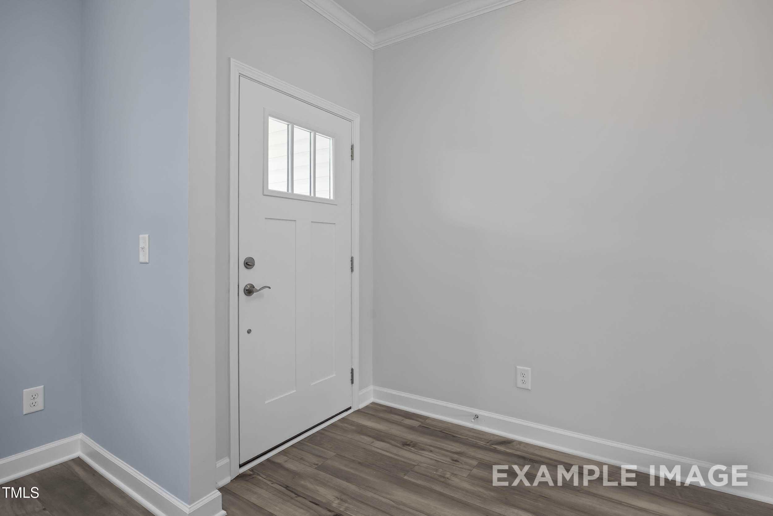 White paneled door with glass insert in entryway, blue accent wall, neutral tones, laminate wood floors in The Willow E home, Angier NC