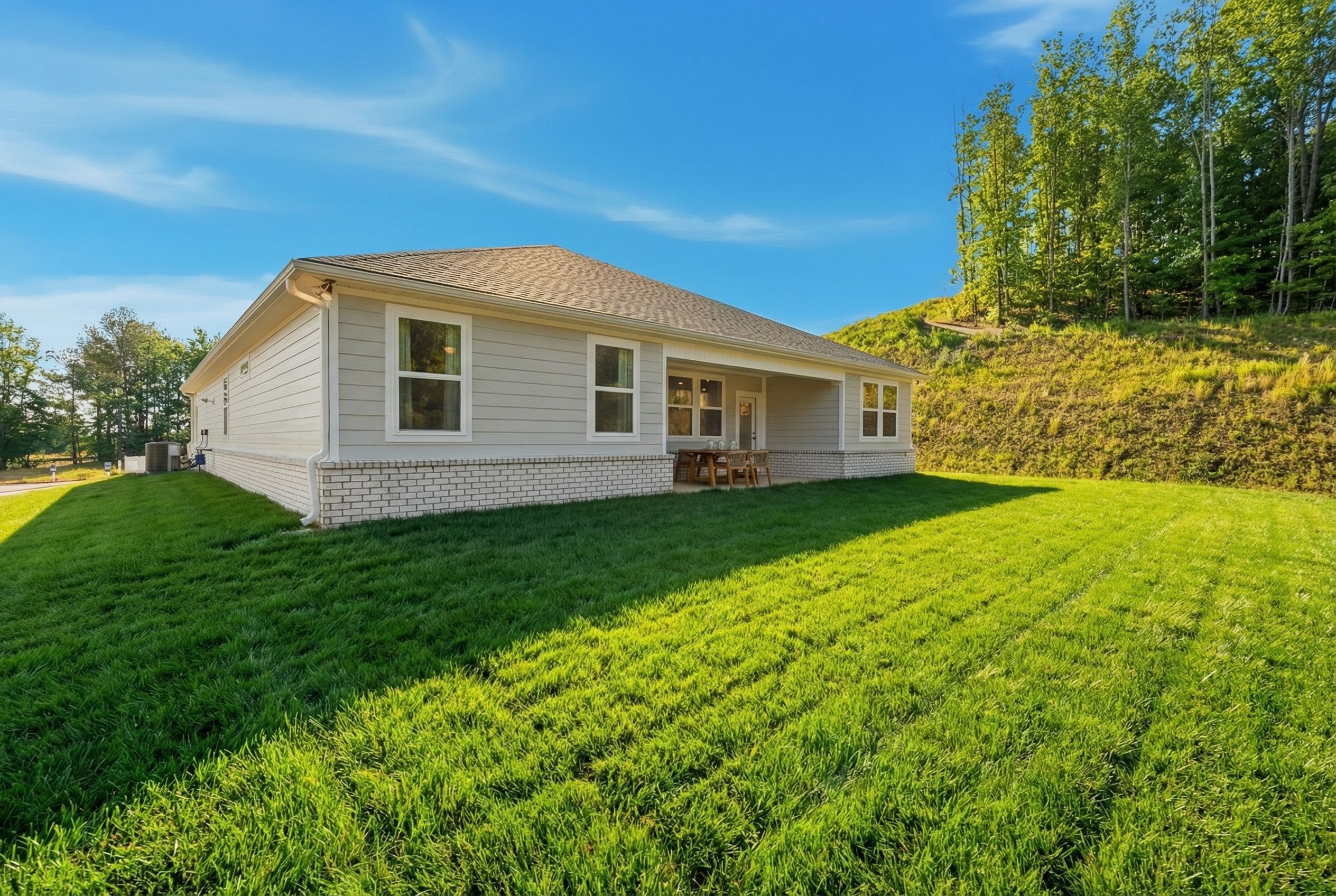 Single-story elevation of The Hibiscus home with CementConcrete exterior, covered patio, garage, and lush green lawn in Cullman AL