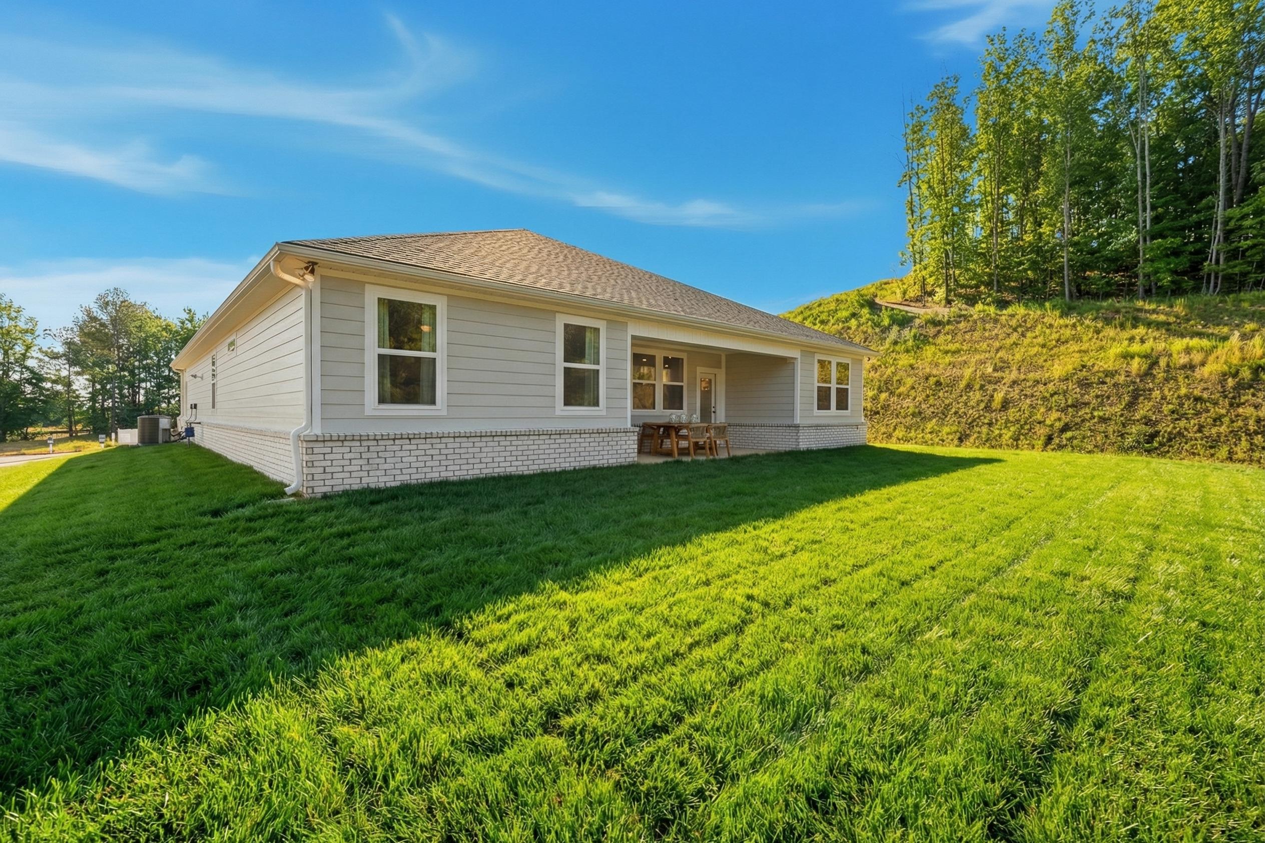 Single-story elevation of The Hibiscus home with CementConcrete exterior, covered patio, garage, and lush green lawn in Cullman AL