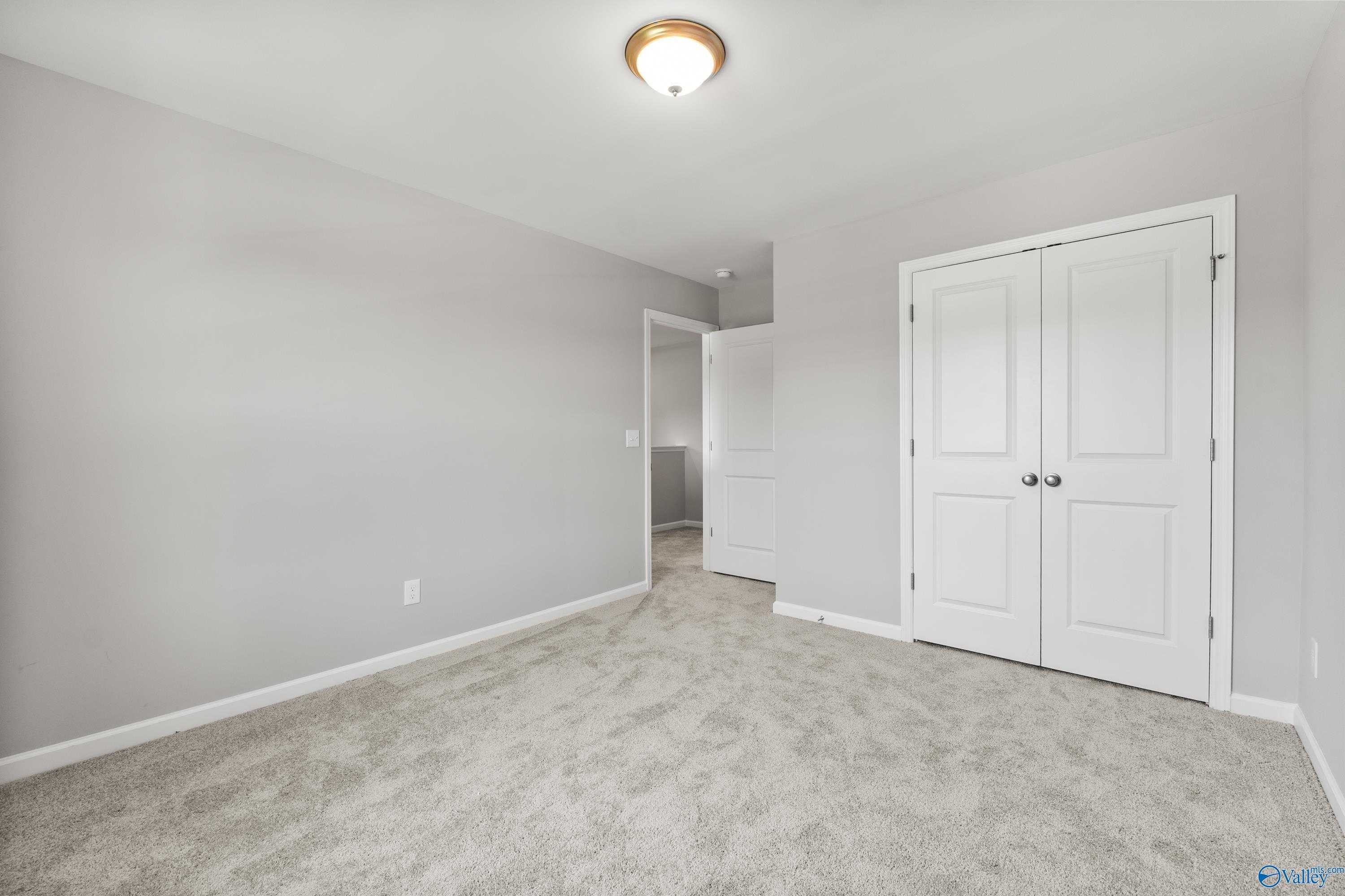Spacious secondary bedroom featuring gray walls, neutral carpet, and double closet doors in Davidson Homes The Charm, Huntsville