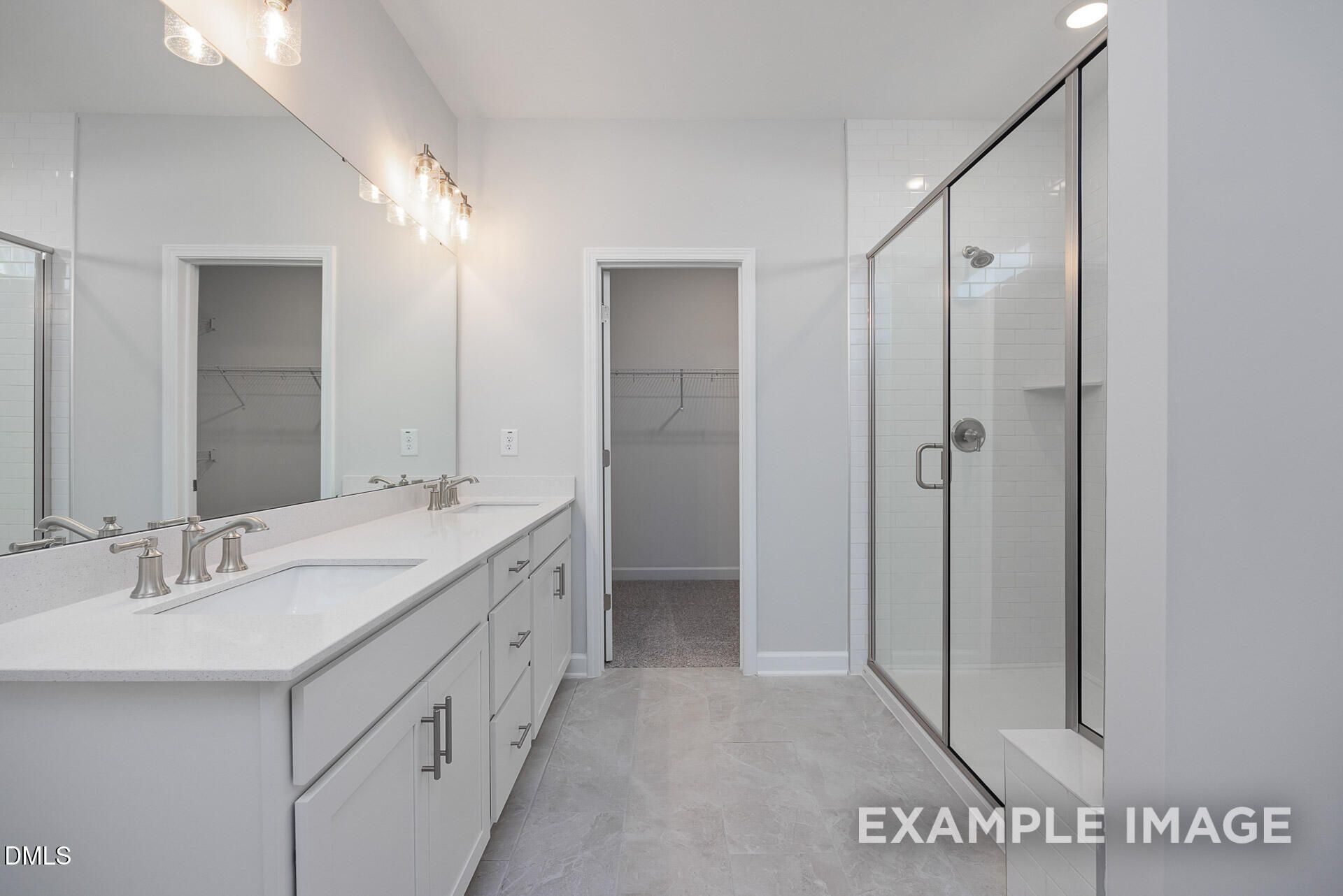 Master bathroom with dual vanity, glass-enclosed shower, and walk-in closet in The Magnolia A, Retreat at North Main.