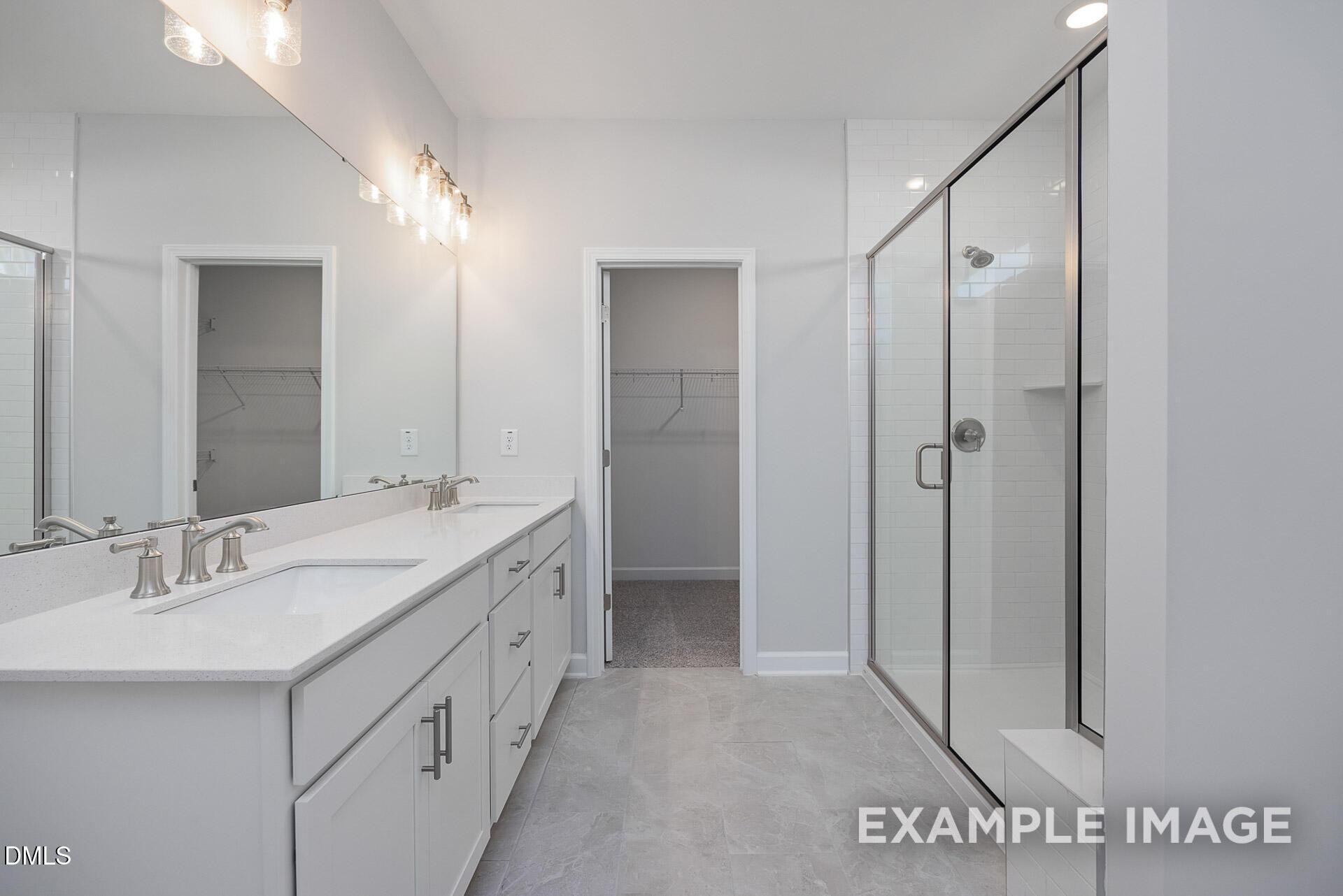 Master bathroom with dual vanity, glass-enclosed shower, and walk-in closet in The Magnolia A, Retreat at North Main.