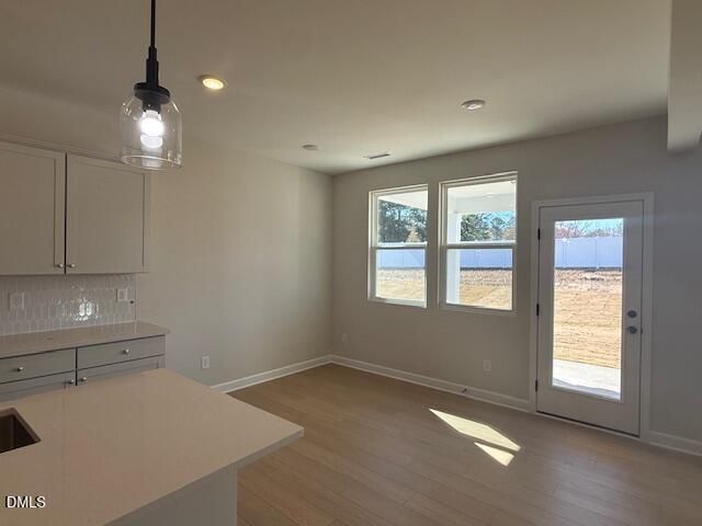 Bright modern kitchen with white shaker cabinets, quartz counters, pendant light, and large windows to backyard in The Willow D, Zebulon, NC