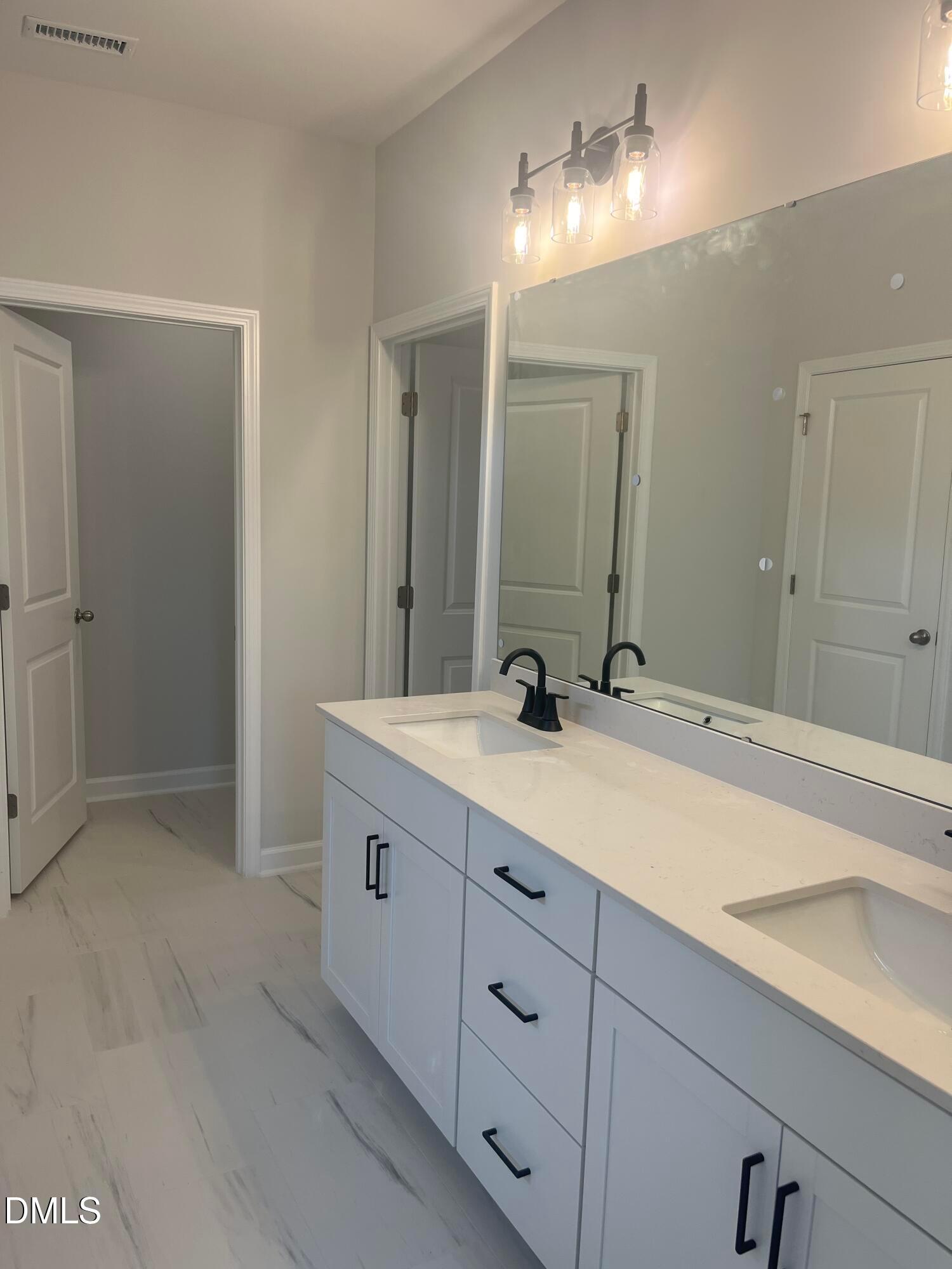 Modern primary bathroom with double vanity, quartz countertop, white cabinets, and large mirror in Davidson Homes The Birch II E, Wake Forest, NC