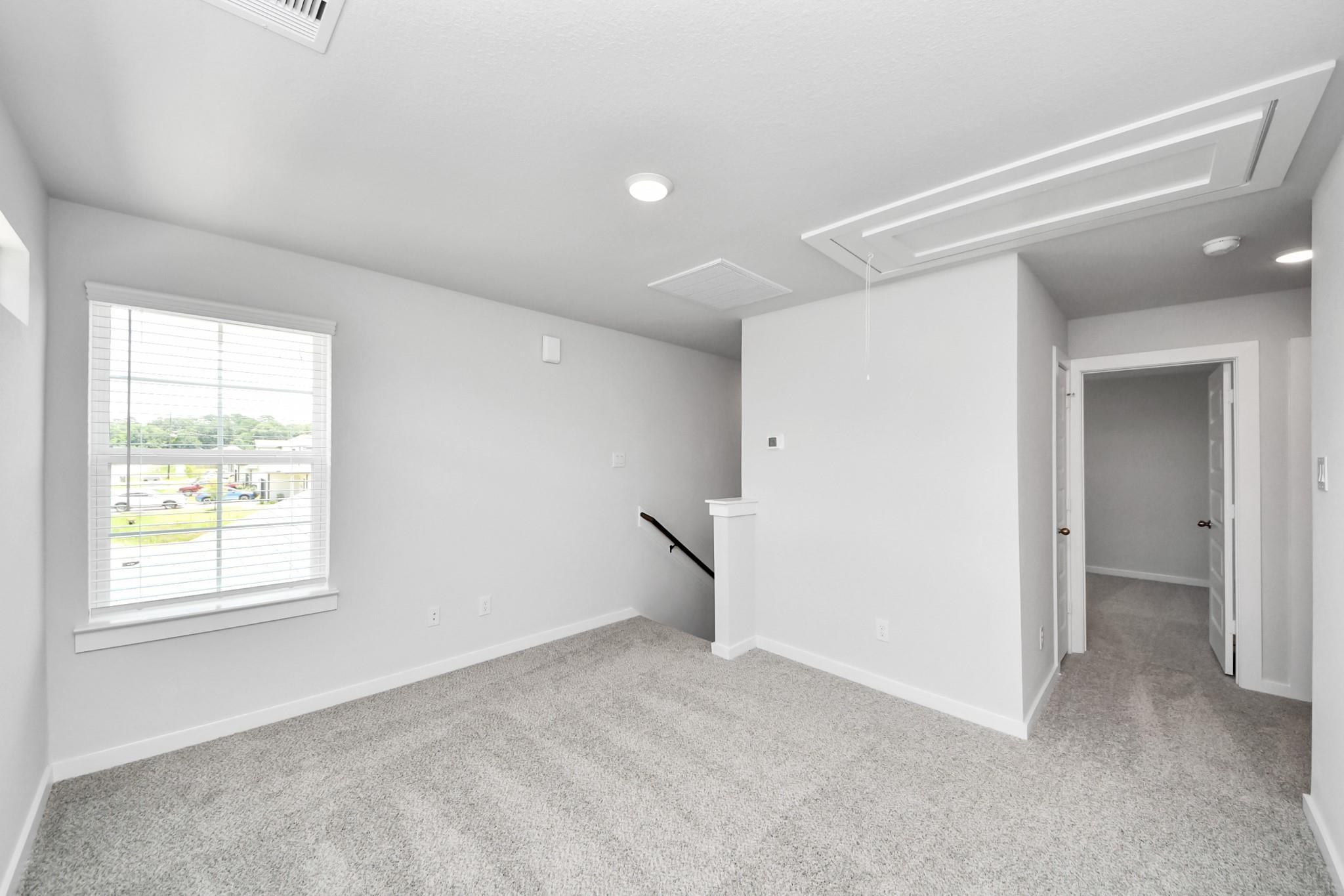 Bright upstairs loft area with plush carpet in The Sabine E floor plan at Liberty Estates, Cleveland, Texas.
