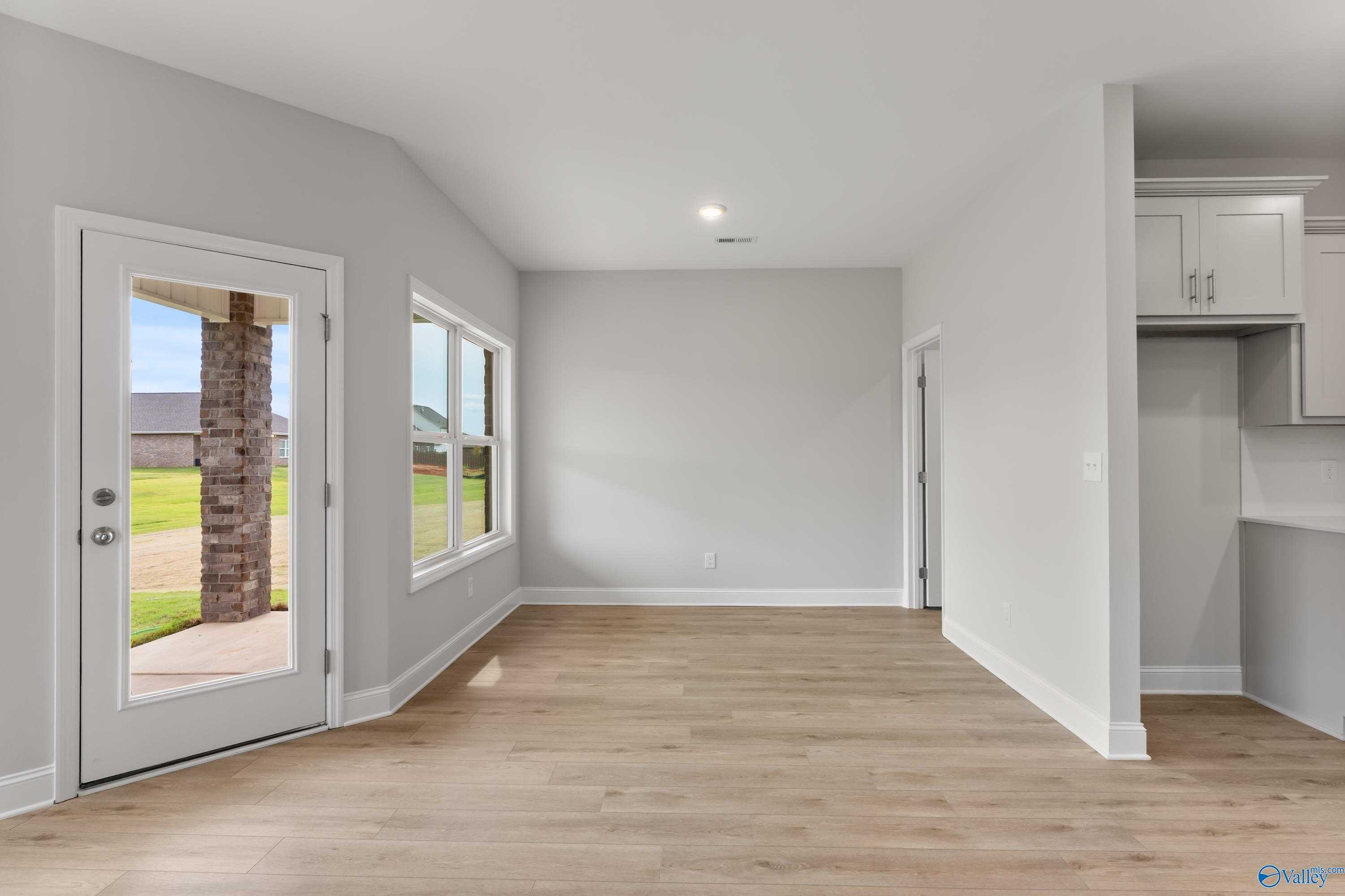 Bright dining nook with hardwood floors, gray walls, and sliding door to grassy backyard in Davidson Homes The Daphne C, Athens AL
