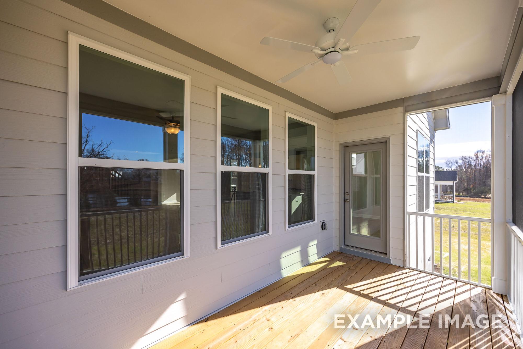 Spacious screened porch in The Cypress C II home with large windows, ceiling fan, wooden floor overlooking Angier NC backyard