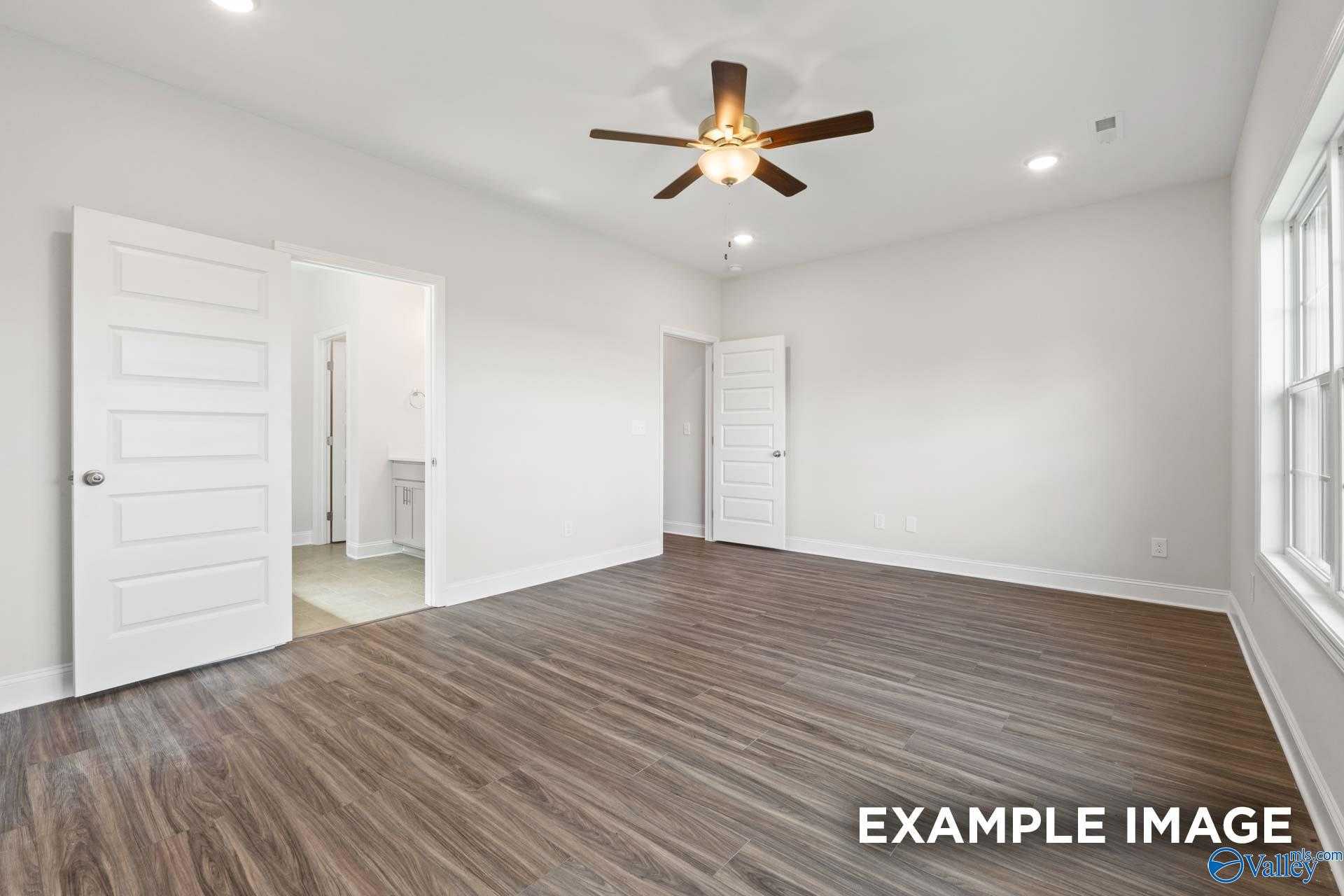 Spacious master bedroom with ceiling fan, wood flooring, and en-suite bathroom doors in Davidson Homes The Montgomery, Athens, Alabama