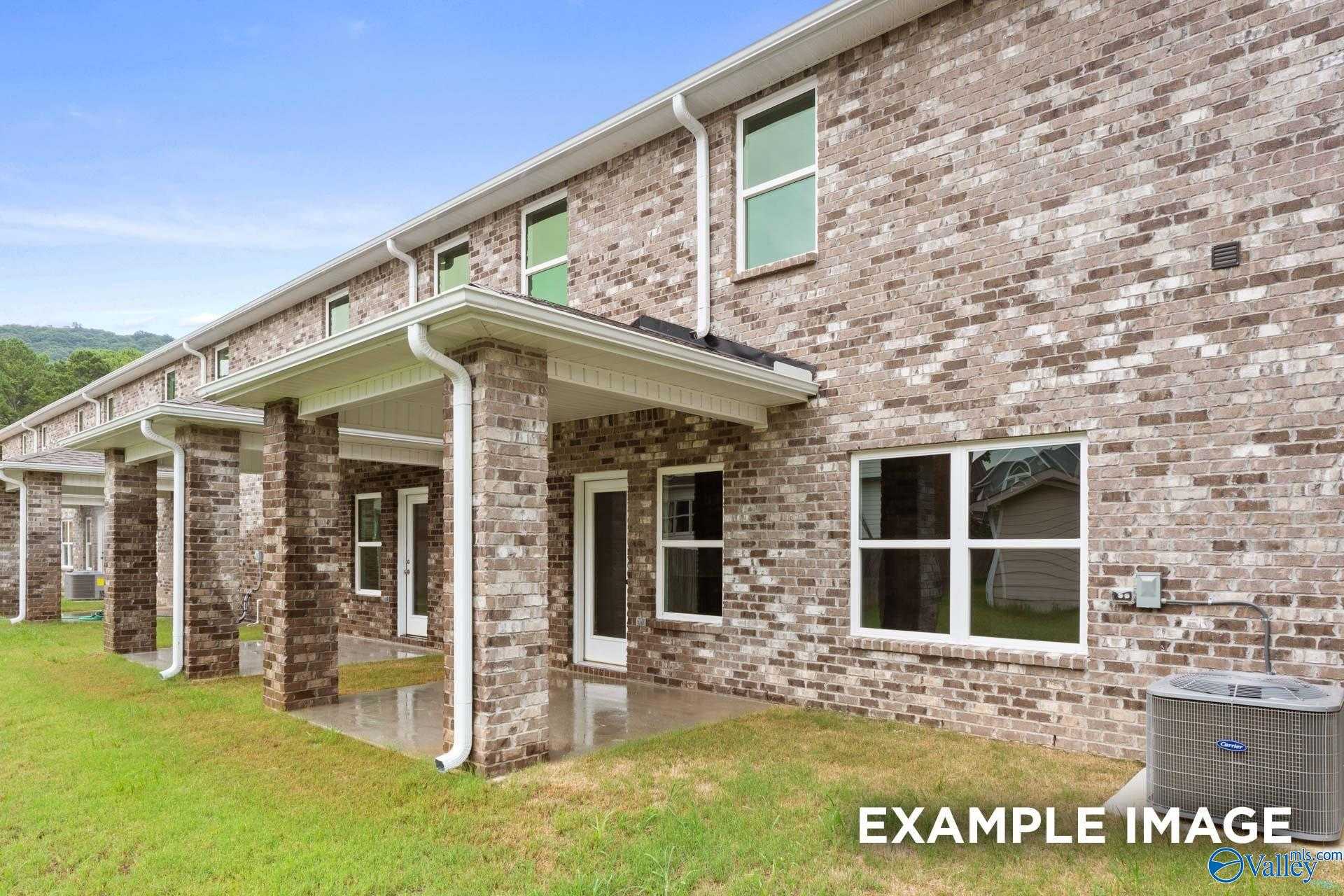 Brick two-story home with covered patio, brick exterior, and lush green yard in Pavilion, Huntsville, Alabama - Davidson Homes The Camden D
