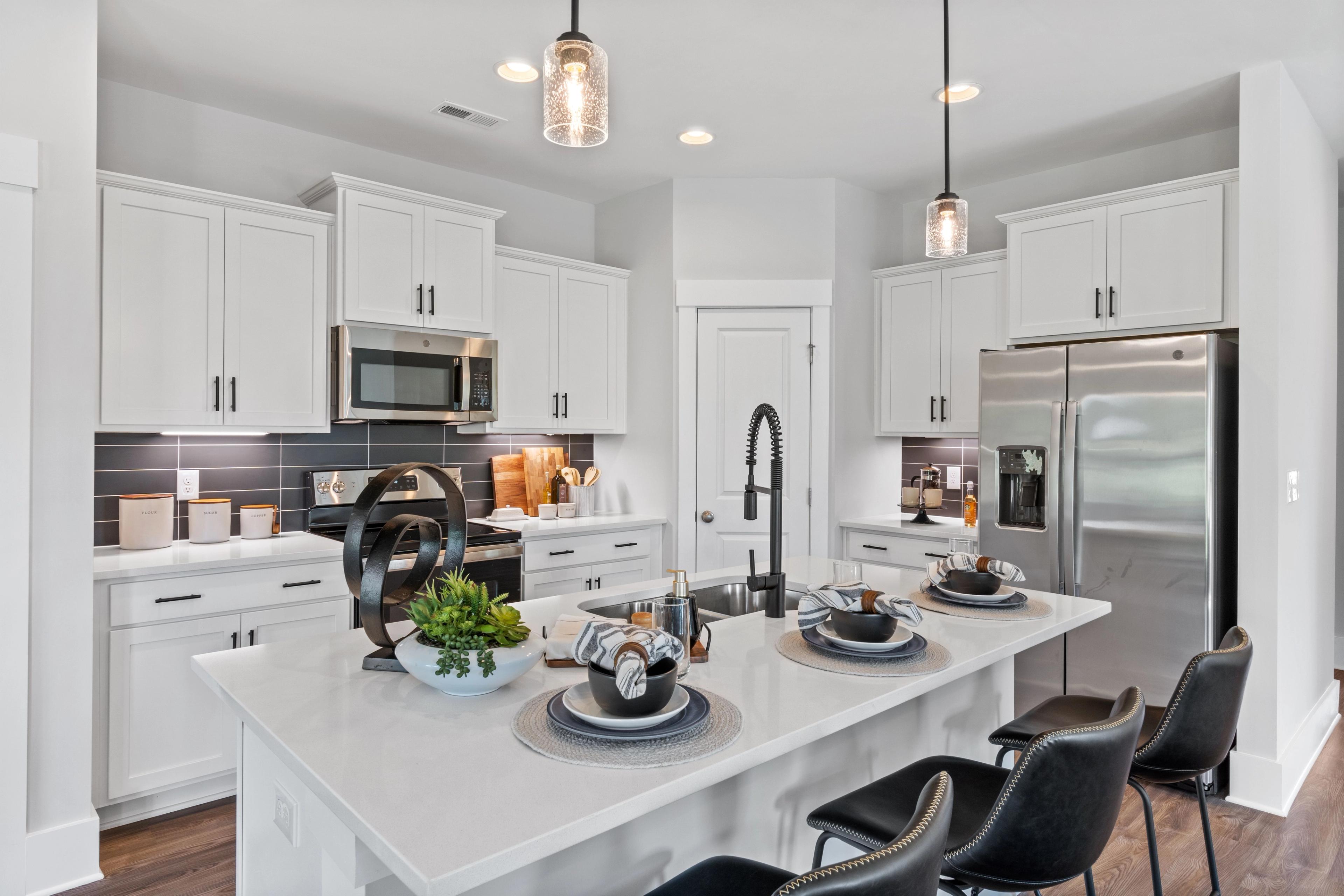 Modern white kitchen in Blue Spring Huntsville AL by Davidson Homes with quartz island black stools stainless appliances