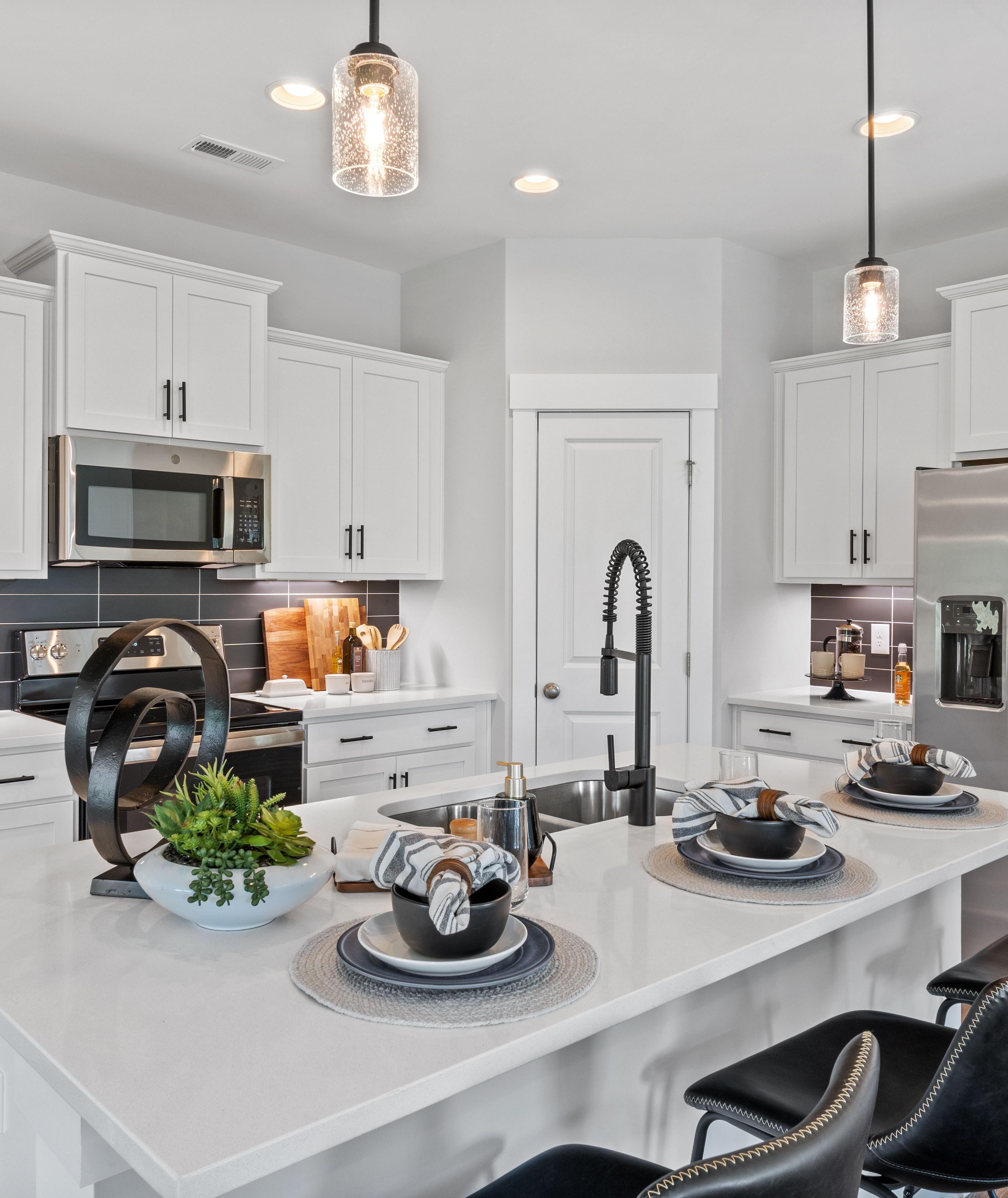 Modern white kitchen in Blue Spring Huntsville AL by Davidson Homes with quartz island black stools stainless appliances