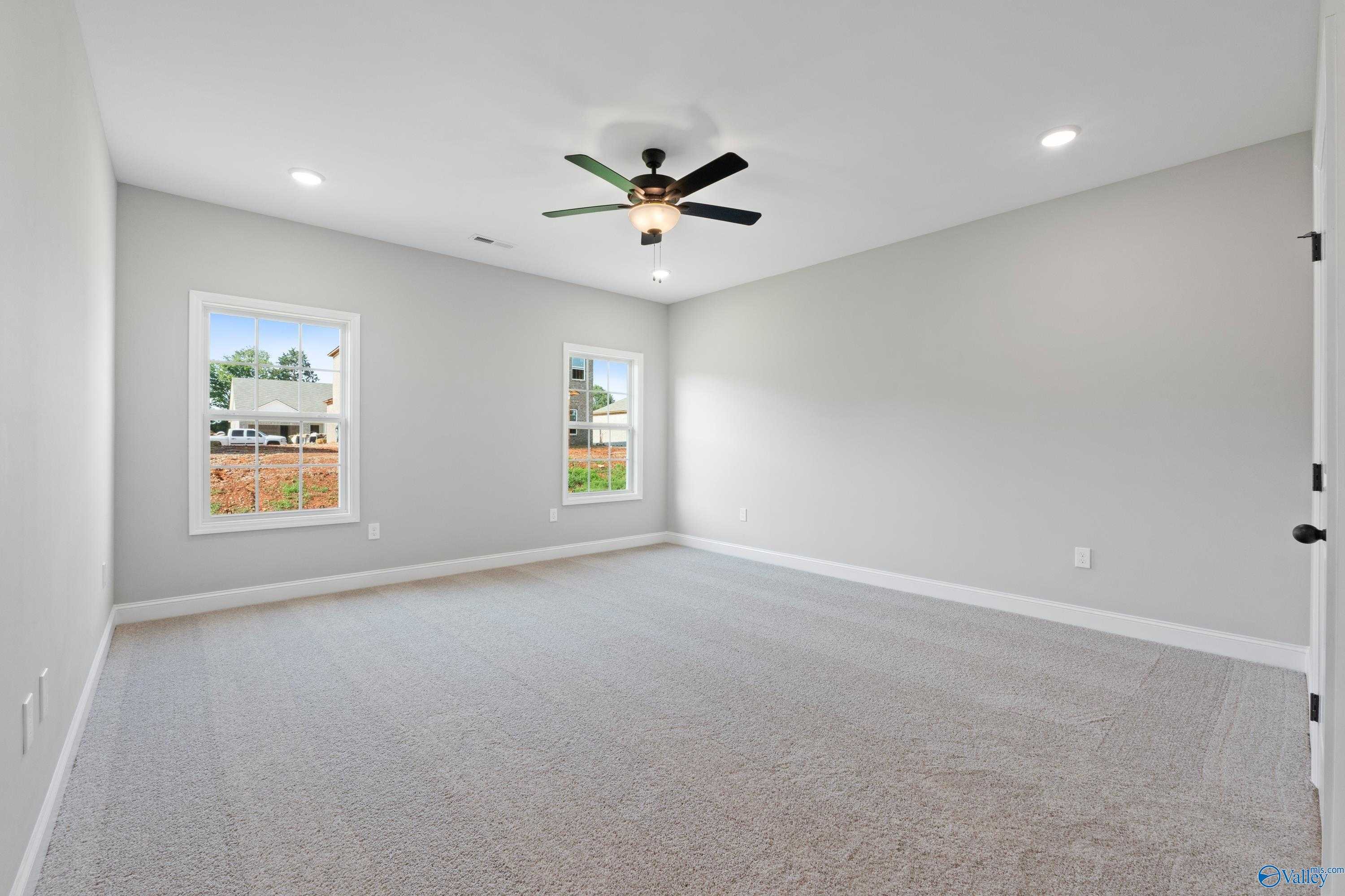Spacious empty bedroom with gray walls, large windows, ceiling fan, and recessed lights in Davidson Homes The Rockford with Bonus, Toney, Alabama