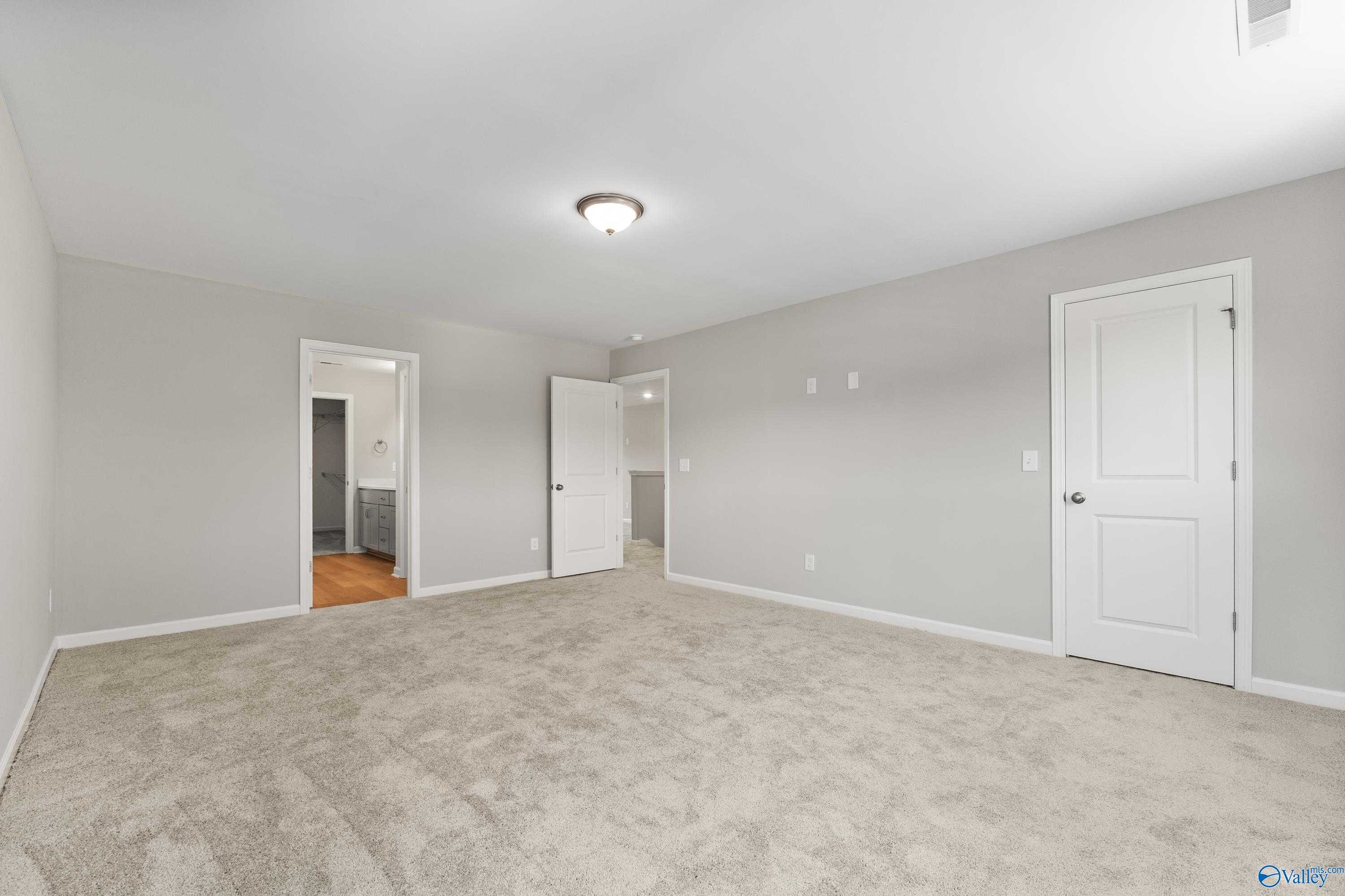 Spacious secondary bedroom with attached bath, beige carpet, gray walls in The Charm 4-bedroom home, Huntsville, AL