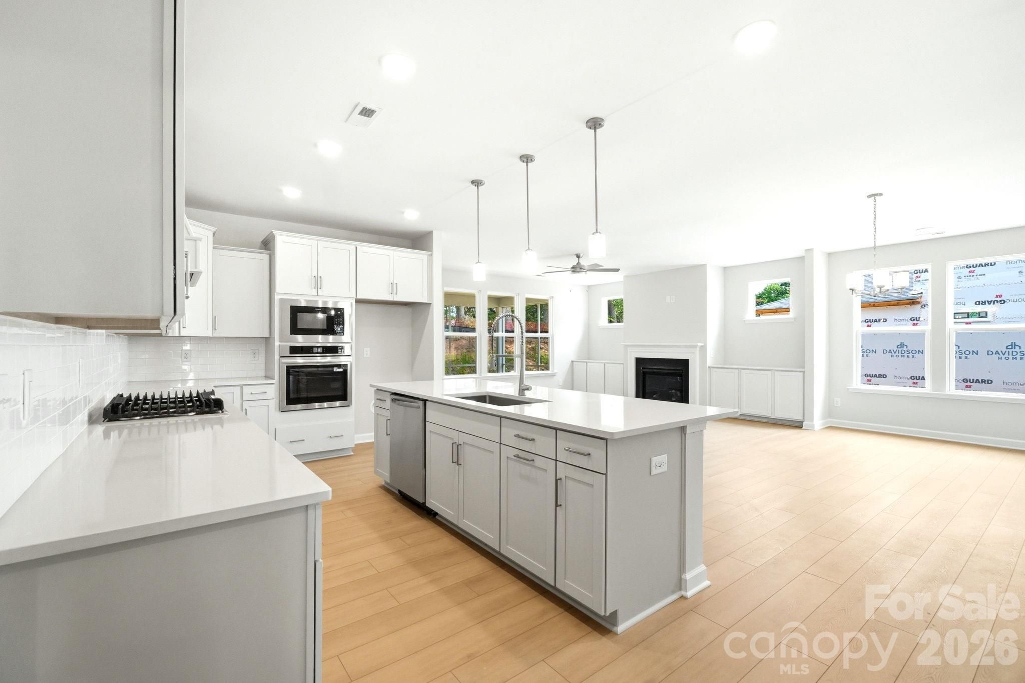 Modern white kitchen with large island and stainless appliances in The Magnolia B floor plan by Davidson Homes in Windgate.