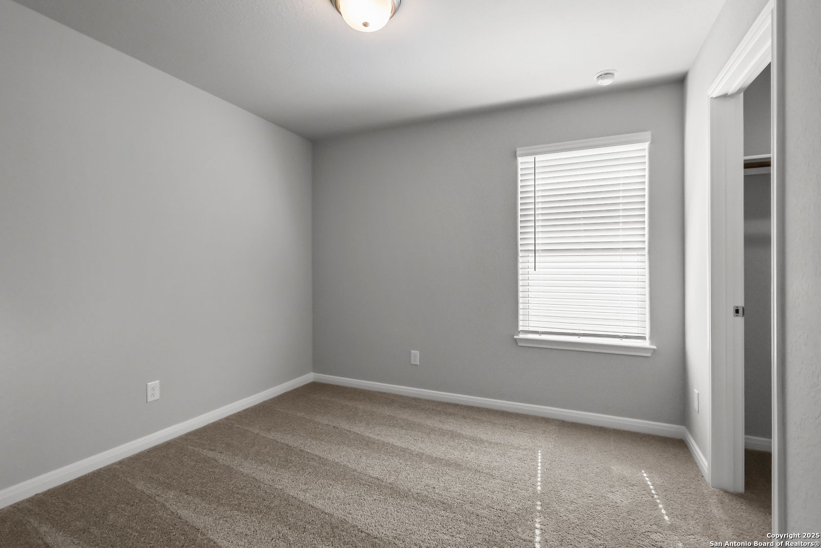 Empty bedroom with gray walls, beige carpet, window blinds, and closet in 5-bedroom Davidson Homes The Gillian C, San Antonio