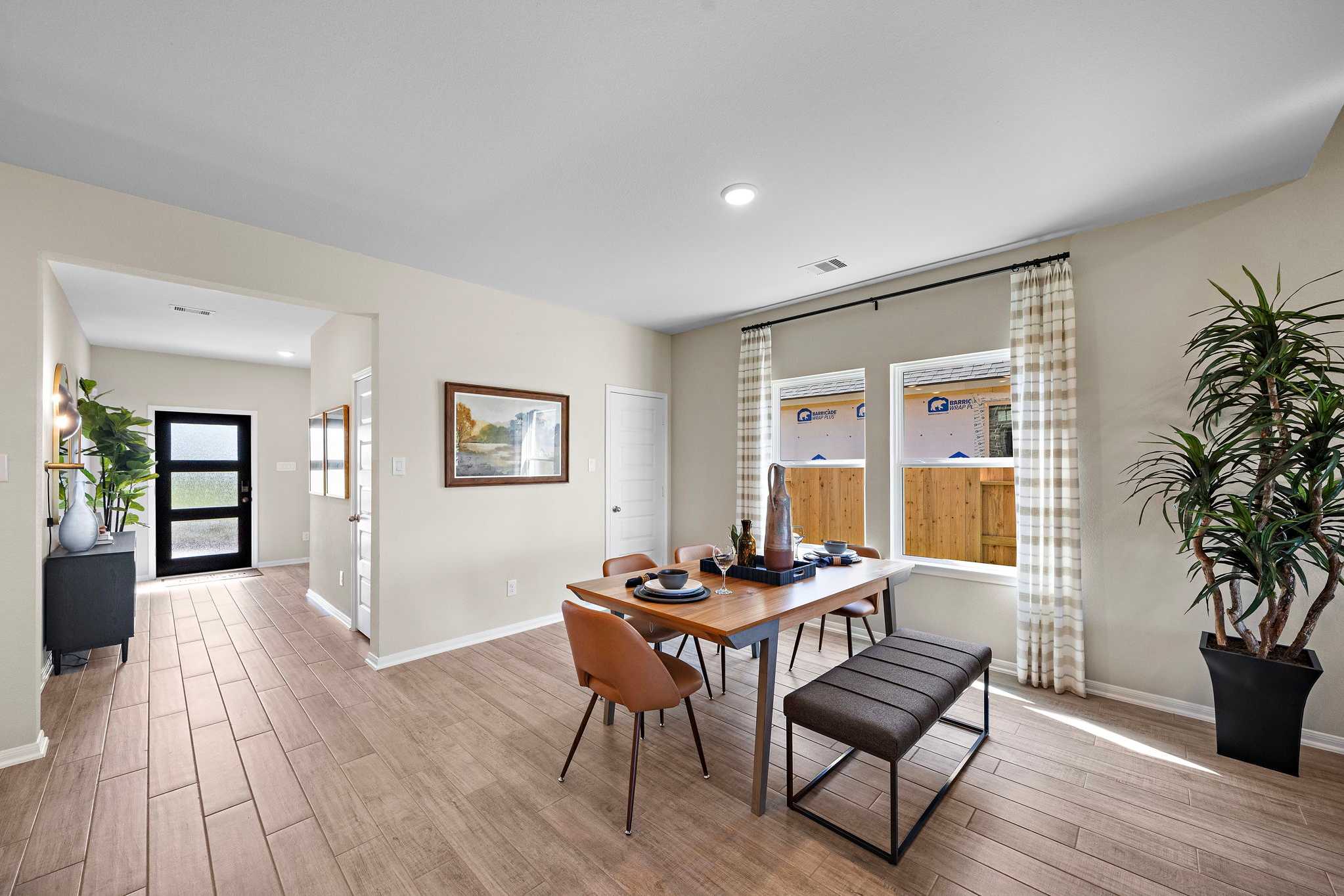 Elegant dining room in Emberly Beasley Texas home by Davidson Homes with hardwood floors, large windows, leather chairs and potted plants