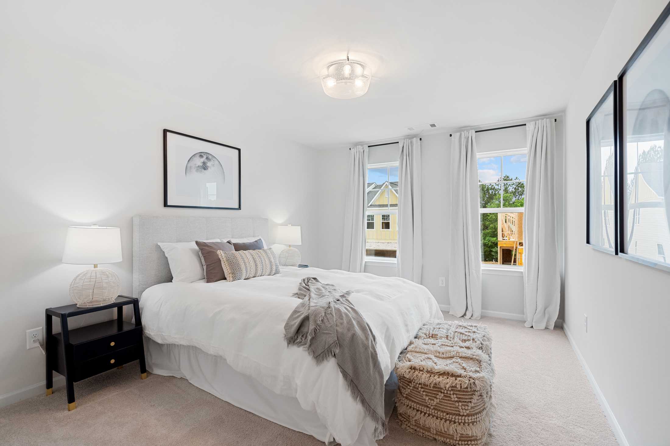 Spacious master bedroom at Rosehill Townhomes in Marietta GA with king bed, white duvet, modern framed art and sheer window curtains