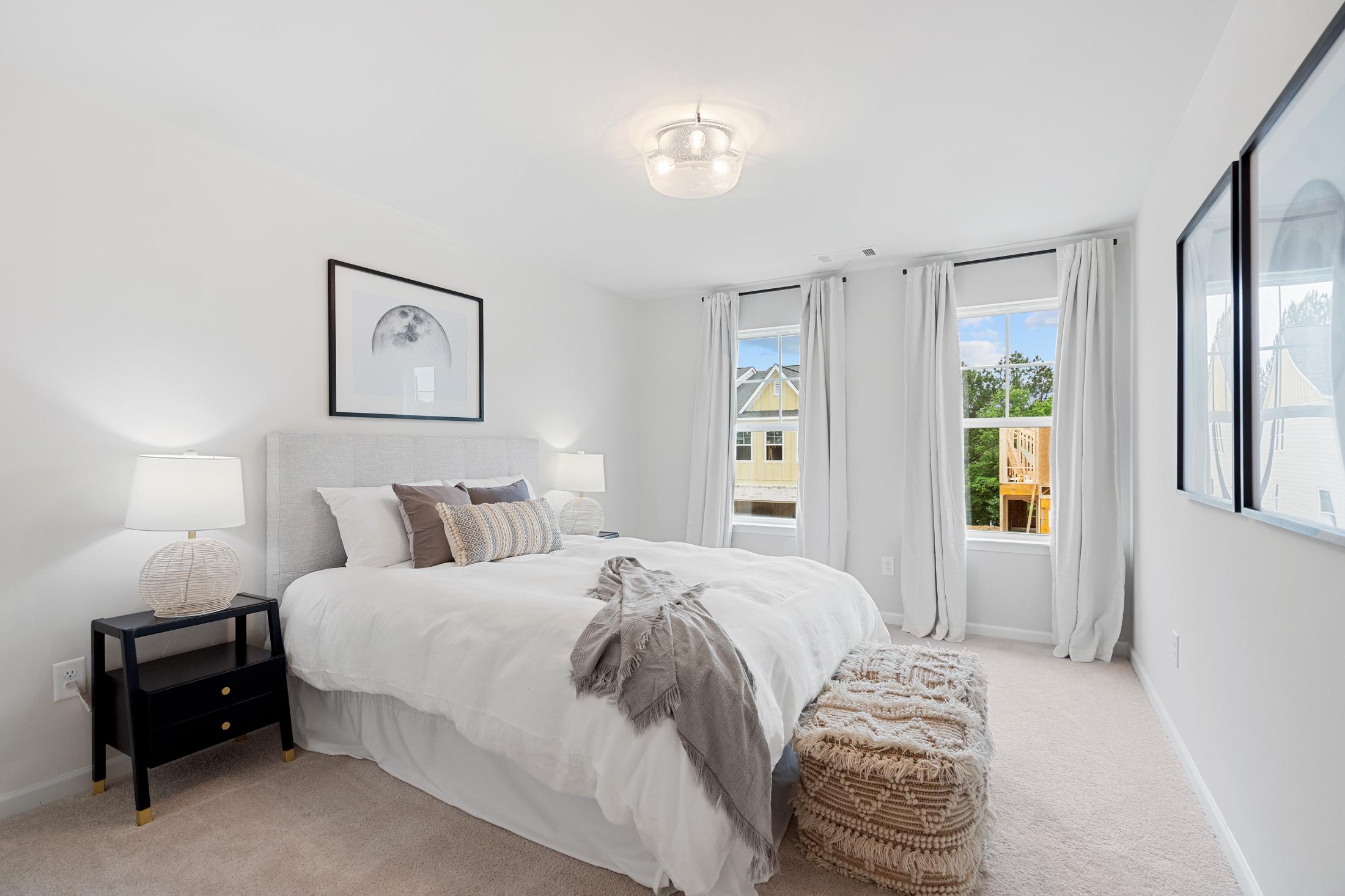 Spacious master bedroom at Rosehill Townhomes in Marietta GA with king bed, white duvet, modern framed art and sheer window curtains