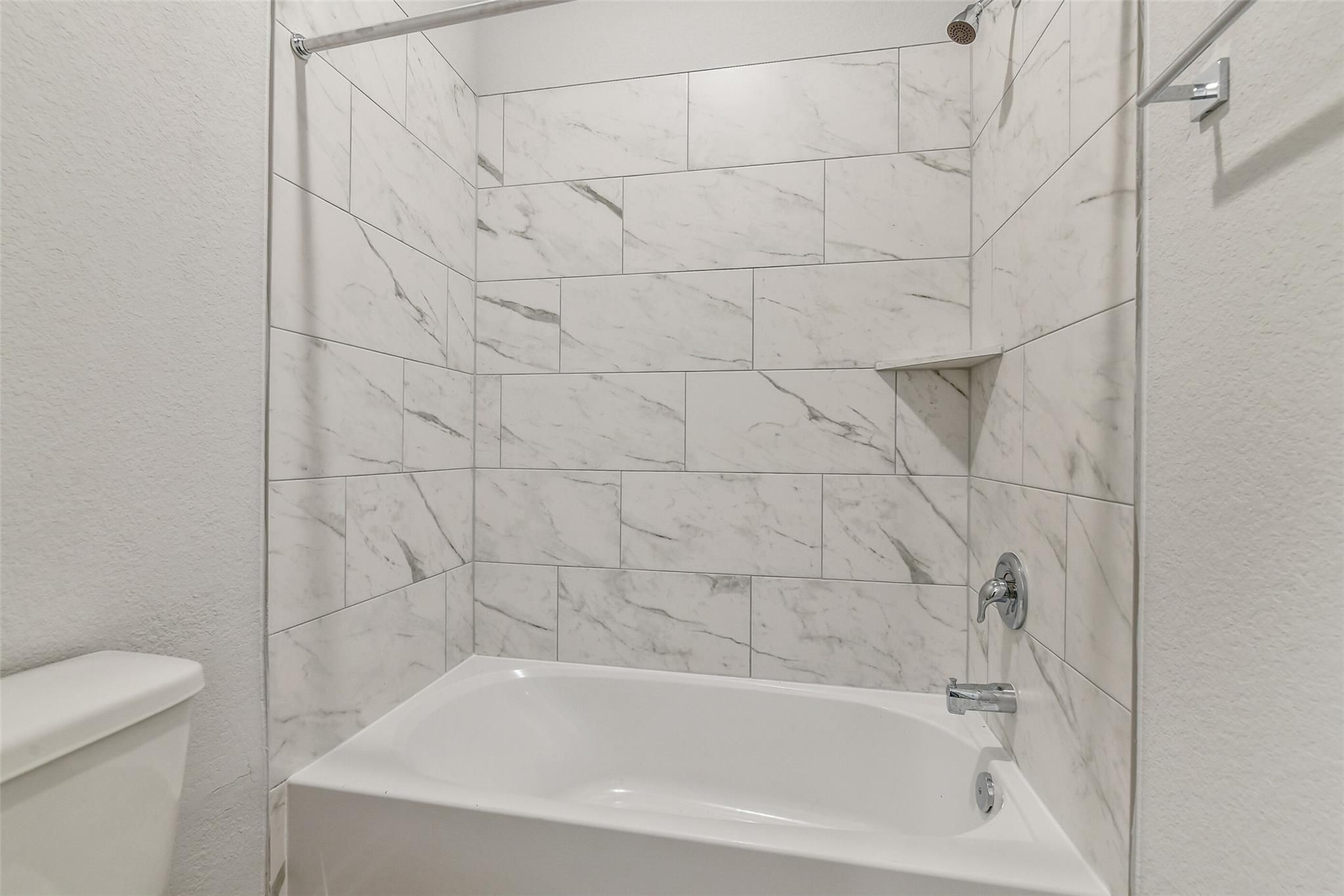 Modern white subway tile shower and soaking tub in 4-bedroom Davidson Homes The Colorado G, Windmill Estates, Magnolia, Texas
