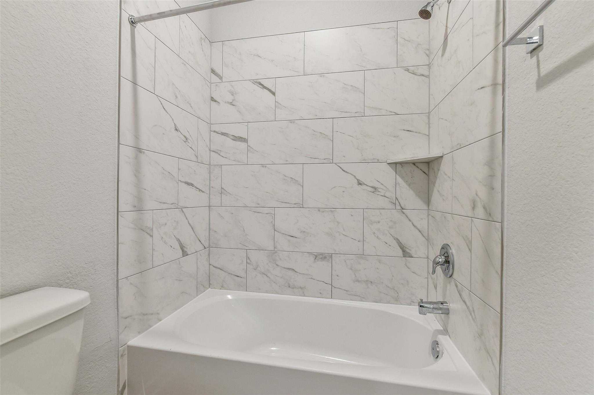 Modern white subway tile shower and soaking tub in 4-bedroom Davidson Homes The Colorado G, Windmill Estates, Magnolia, Texas