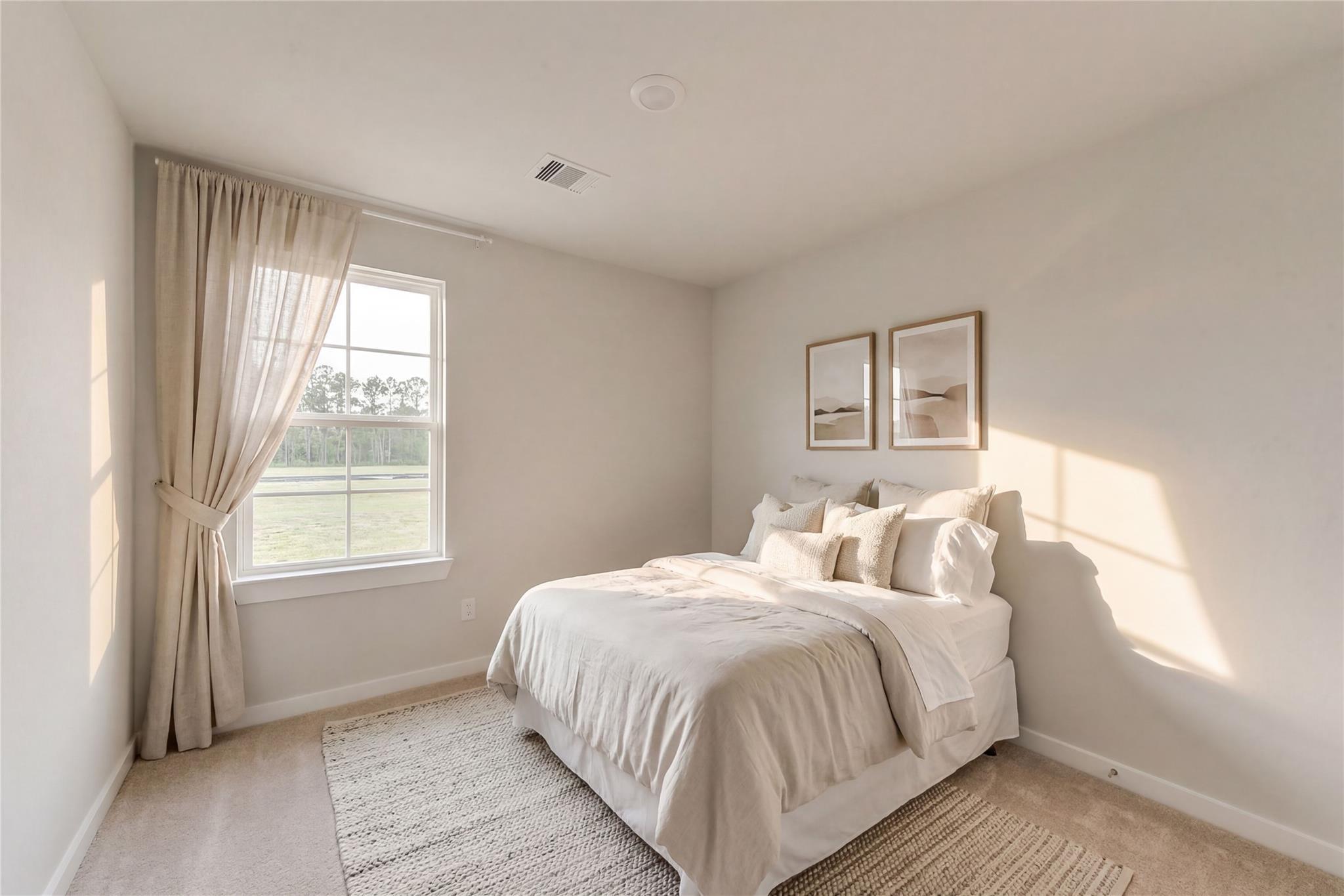 Sunlit bedroom with plush white bed, sheer curtains, and abstract wall art in Davidson Homes The Brazos E, Dayton, Texas