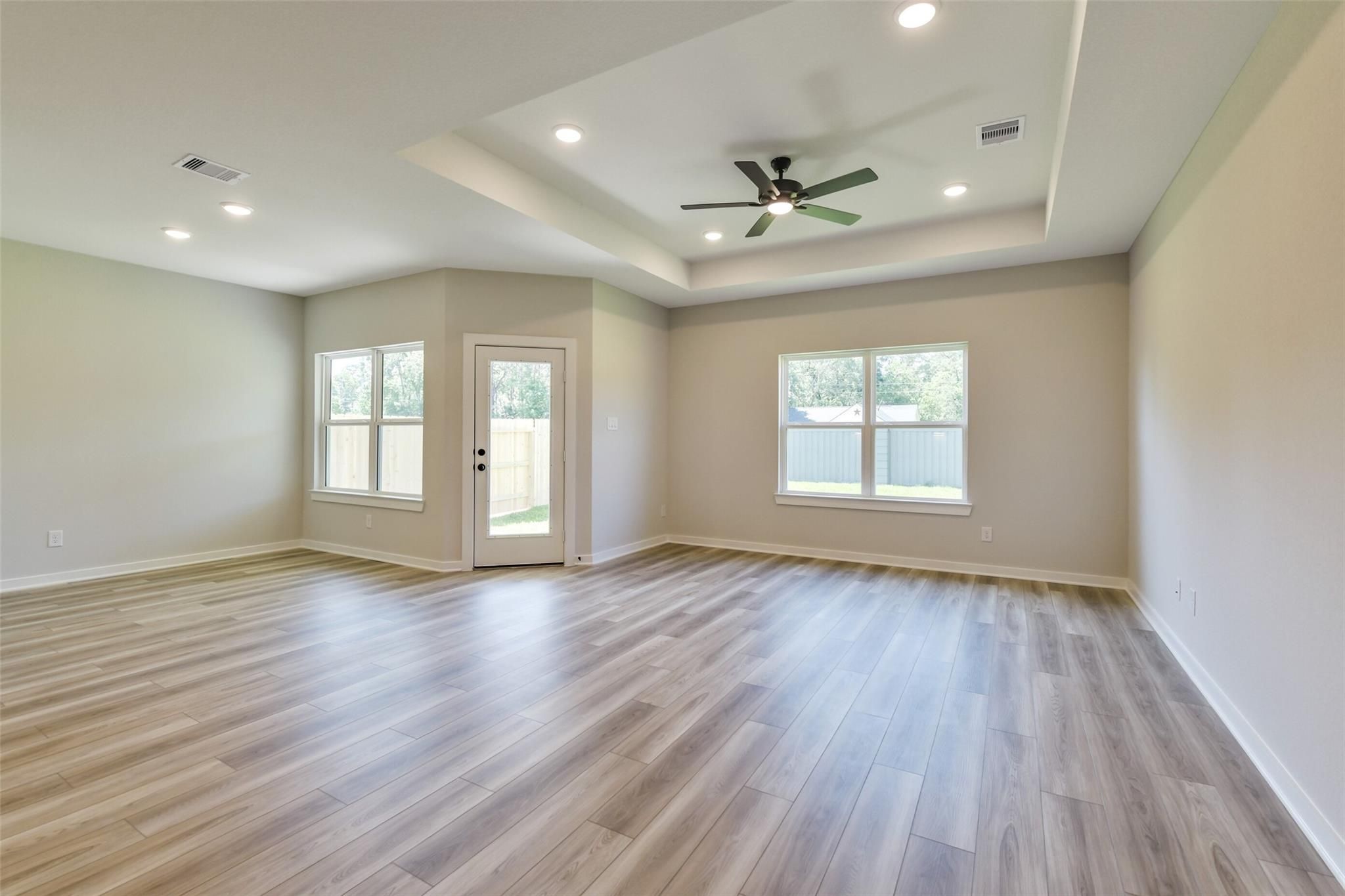 Spacious living room with ceiling fan, large windows, French doors to patio in Davidson Homes The Daphne H, Crosby, Texas
