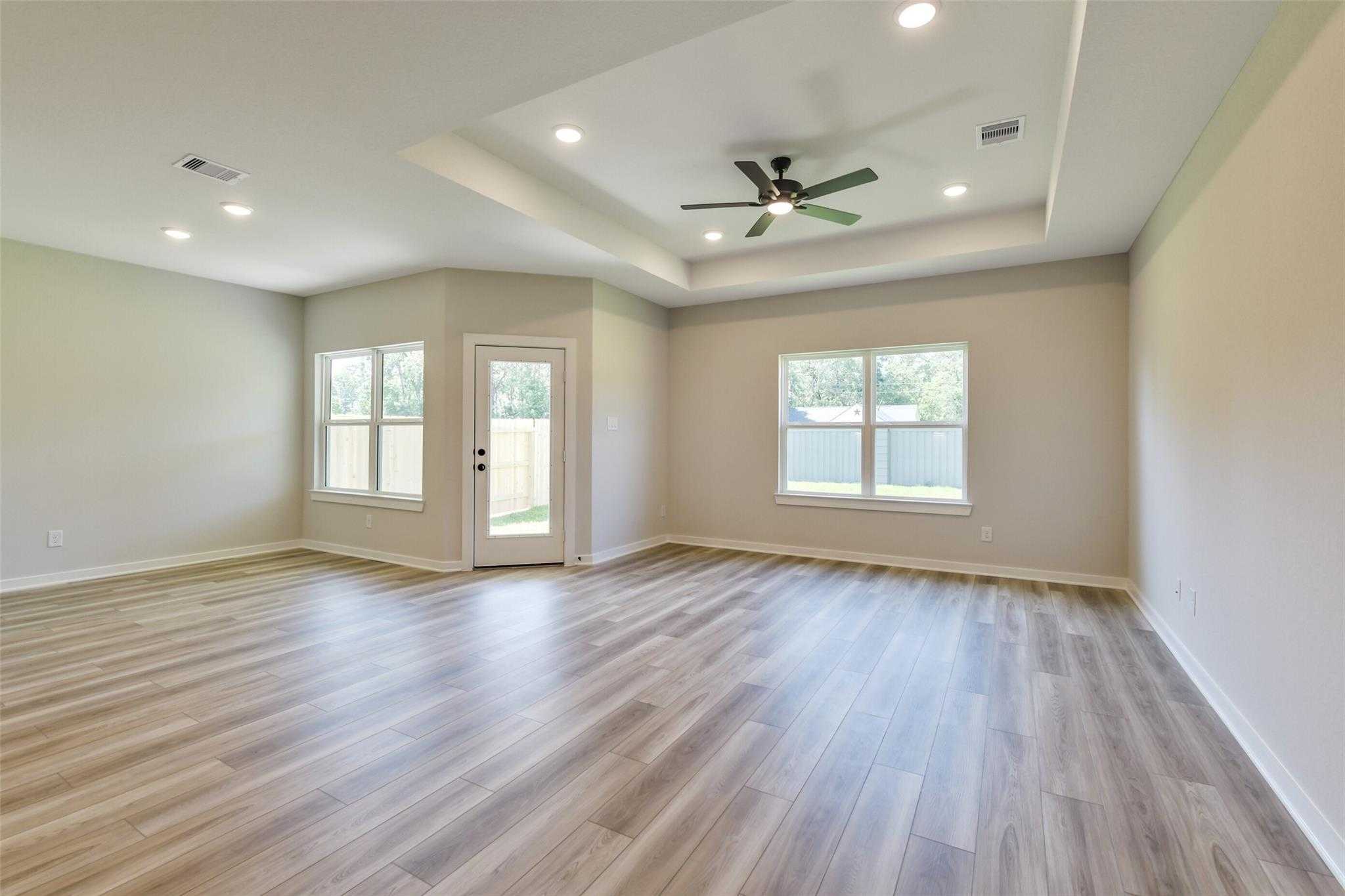 Spacious living room with ceiling fan, large windows, French doors to patio in Davidson Homes The Daphne H, Crosby, Texas