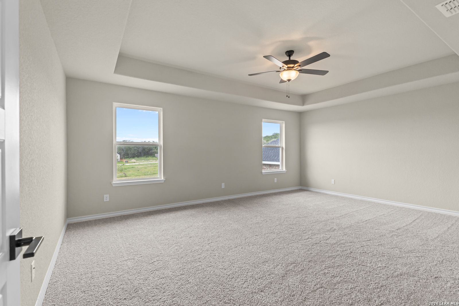 Spacious primary bedroom with tray ceiling and ceiling fan in The Danbury H floor plan at The Reserve at Potranco Oaks.