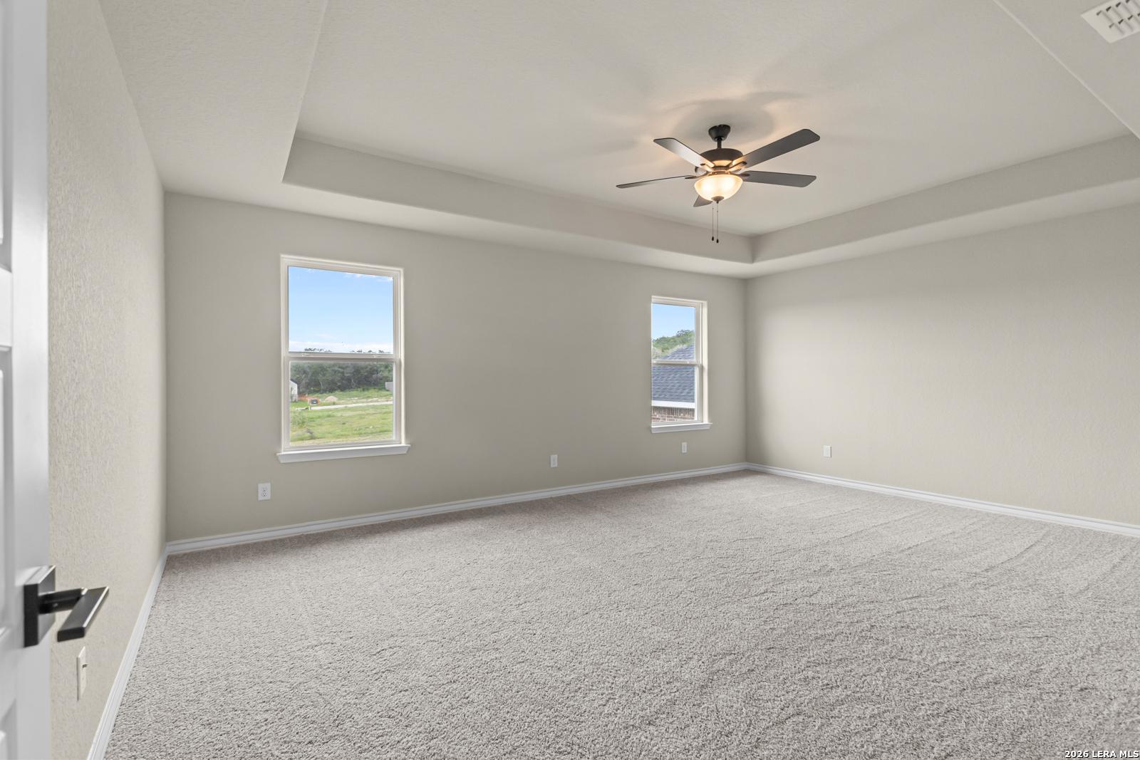 Spacious primary bedroom with tray ceiling and ceiling fan in The Danbury H floor plan at The Reserve at Potranco Oaks.