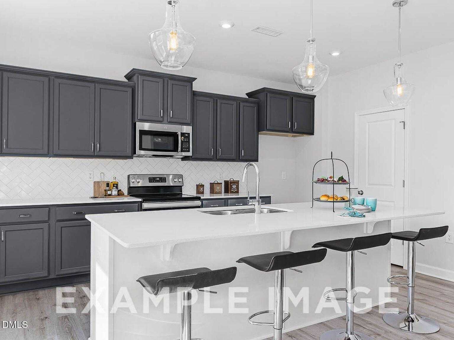 Open-concept kitchen with gray shaker cabinets, white quartz island, stainless appliances, and pendant lights in Davidson Homes Chestnut B, Lillington, NC