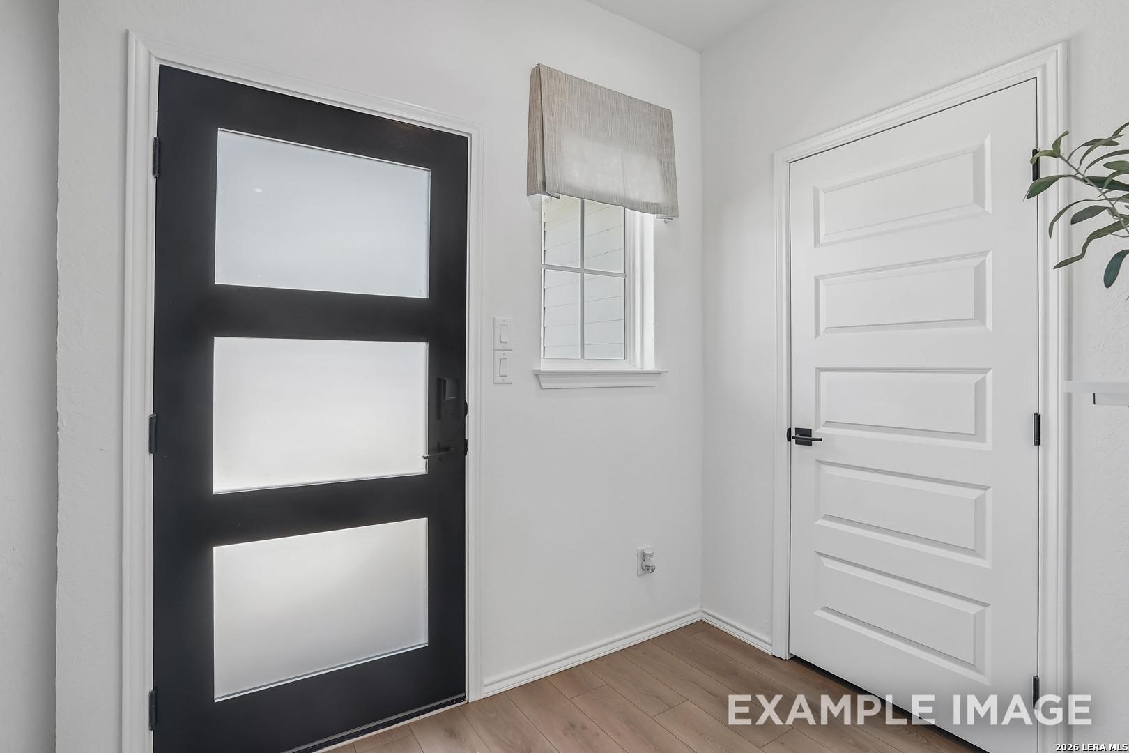 Modern black front door with frosted glass panels and white interior at Davidson Homes The Pinecrest F in Morgan Meadows, San Antonio, Texas