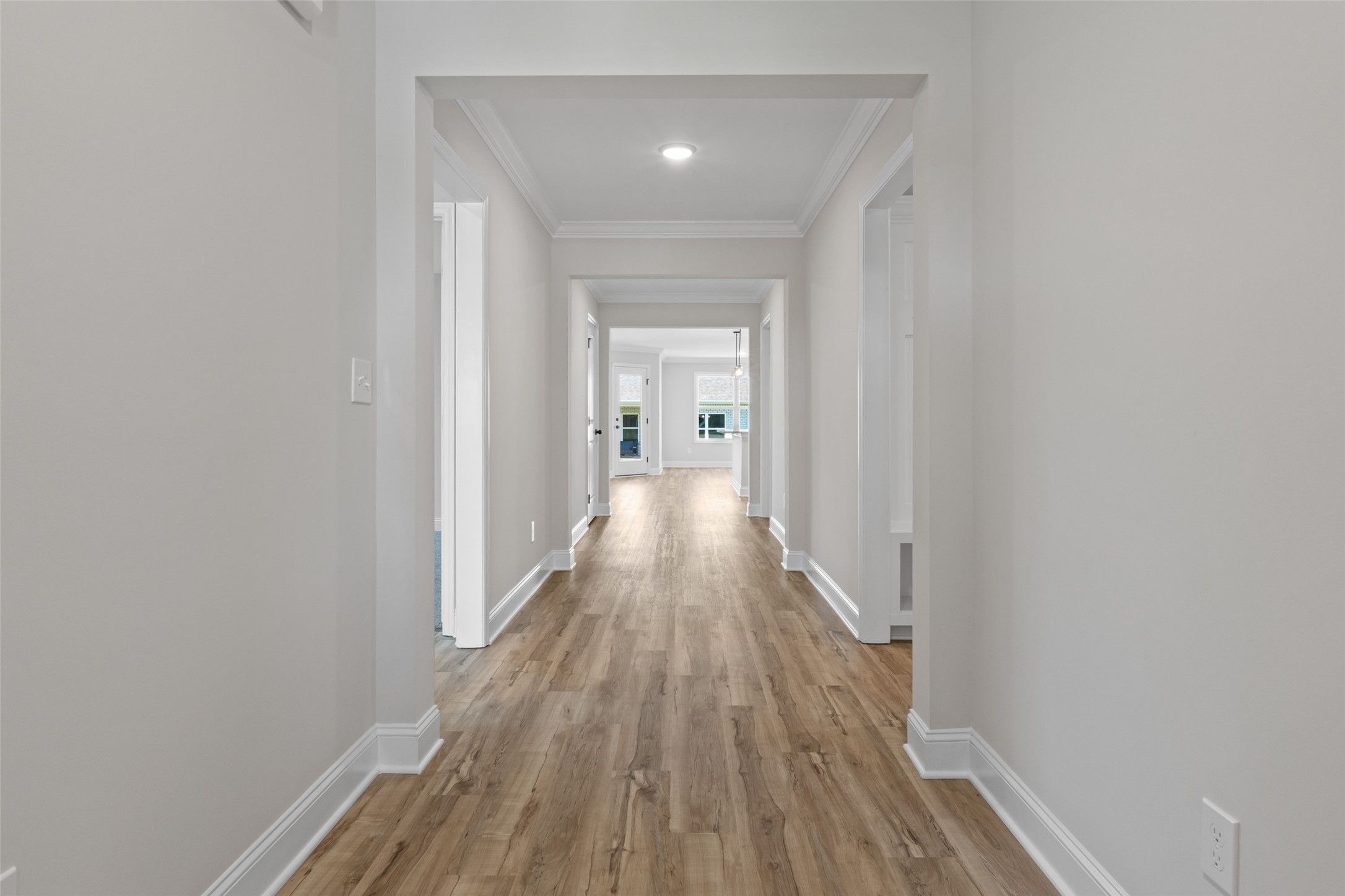 Bright hallway with wood-look flooring leading to open living area in The Holly C floor plan, Parks at Foster Crossing.
